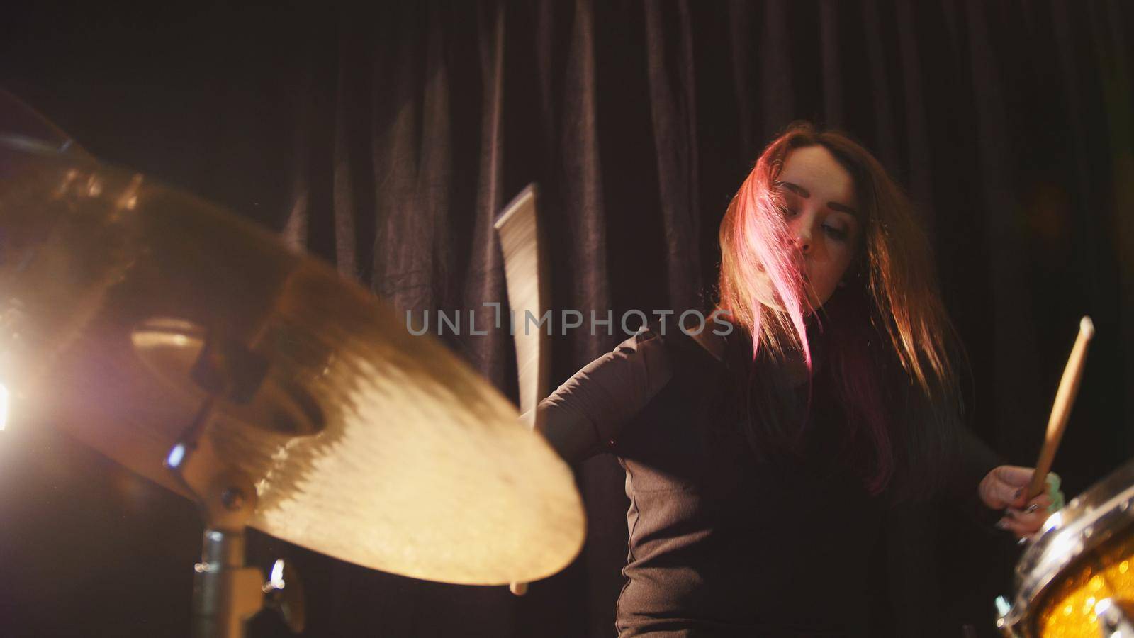 Flowing black hair - beauty girl plays drum rock at garage, close up