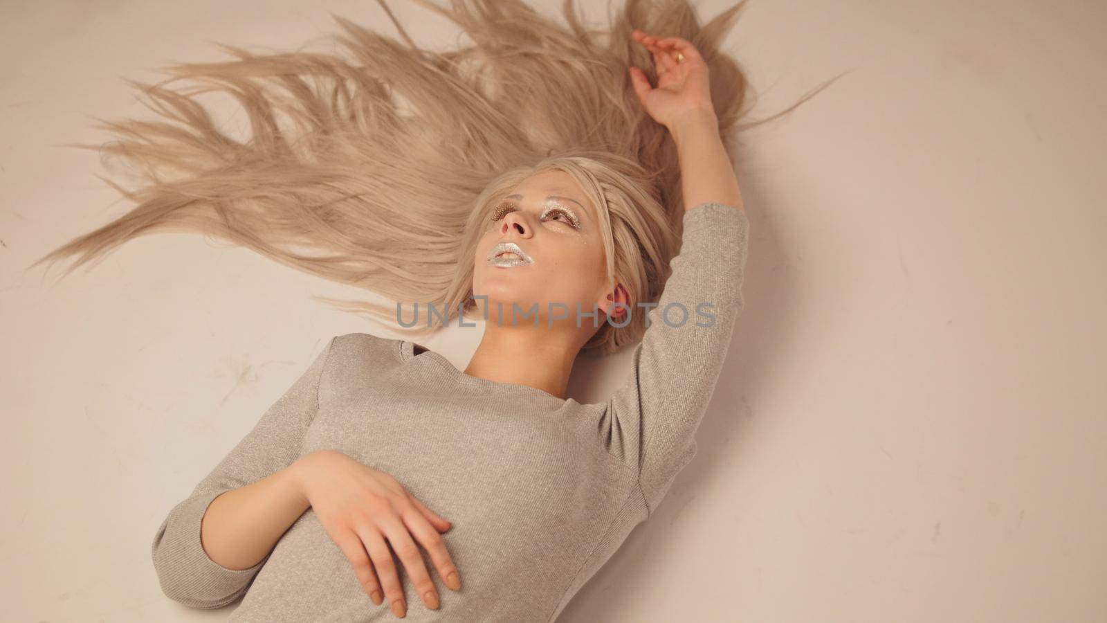 Blonde model girl lying in photo studio - close up view, white background
