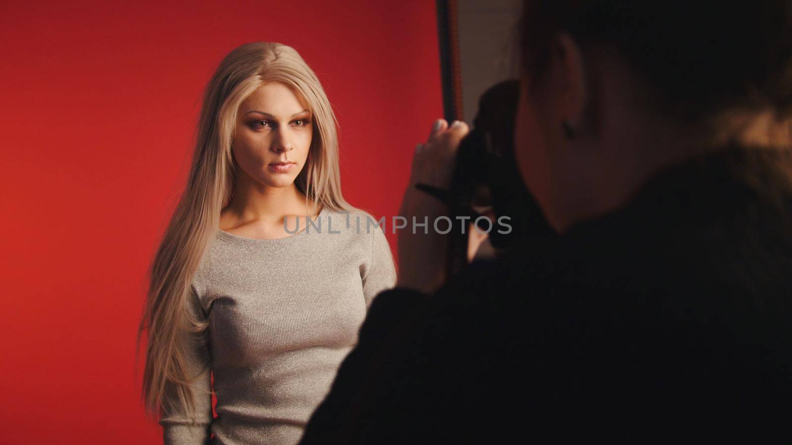 Blondy girl posing for photographer - fashion backstage, red background