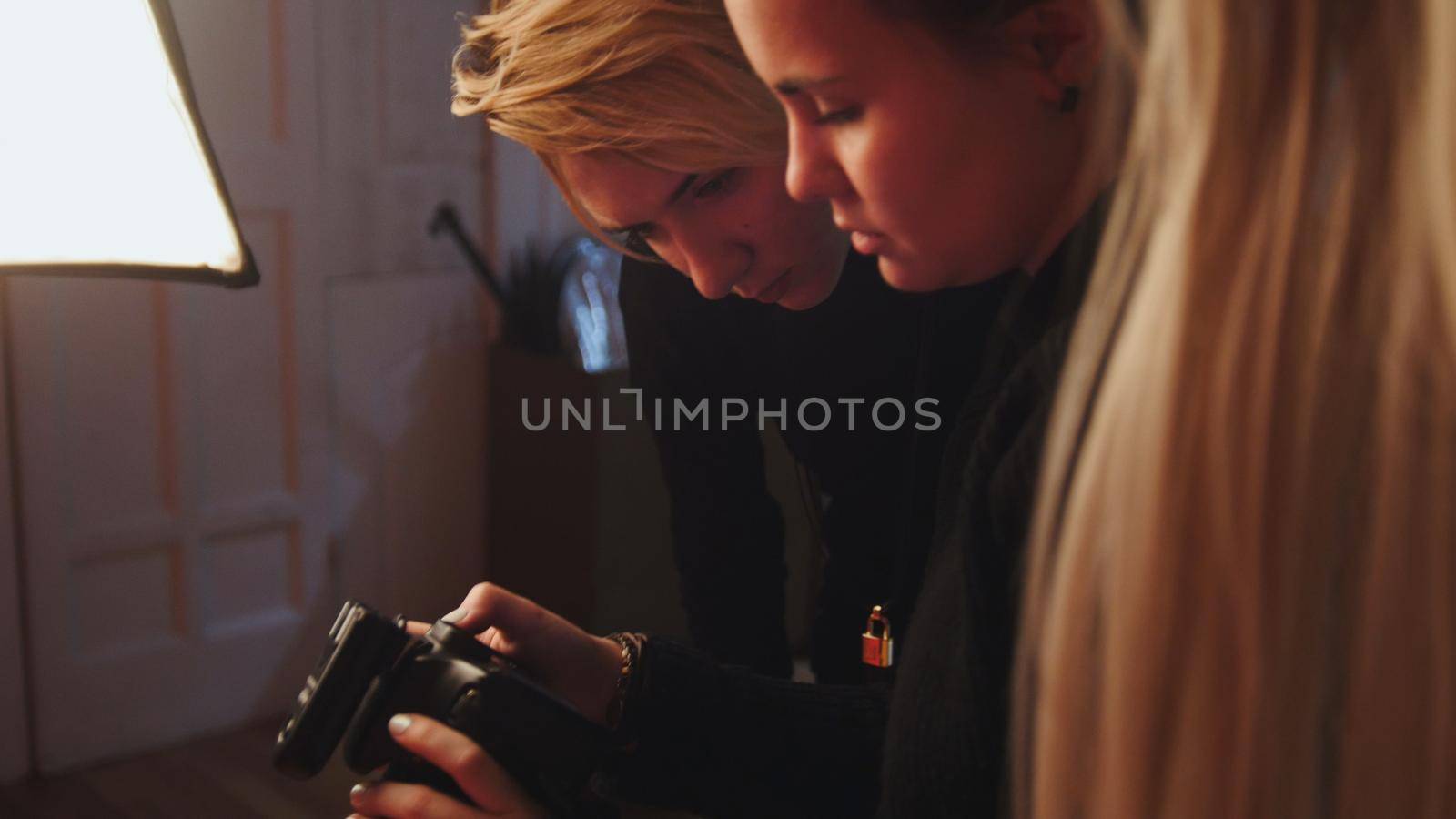 Blonde girl model and photographer in photo studio watching photos in camera, fashion backstage by Studia72
