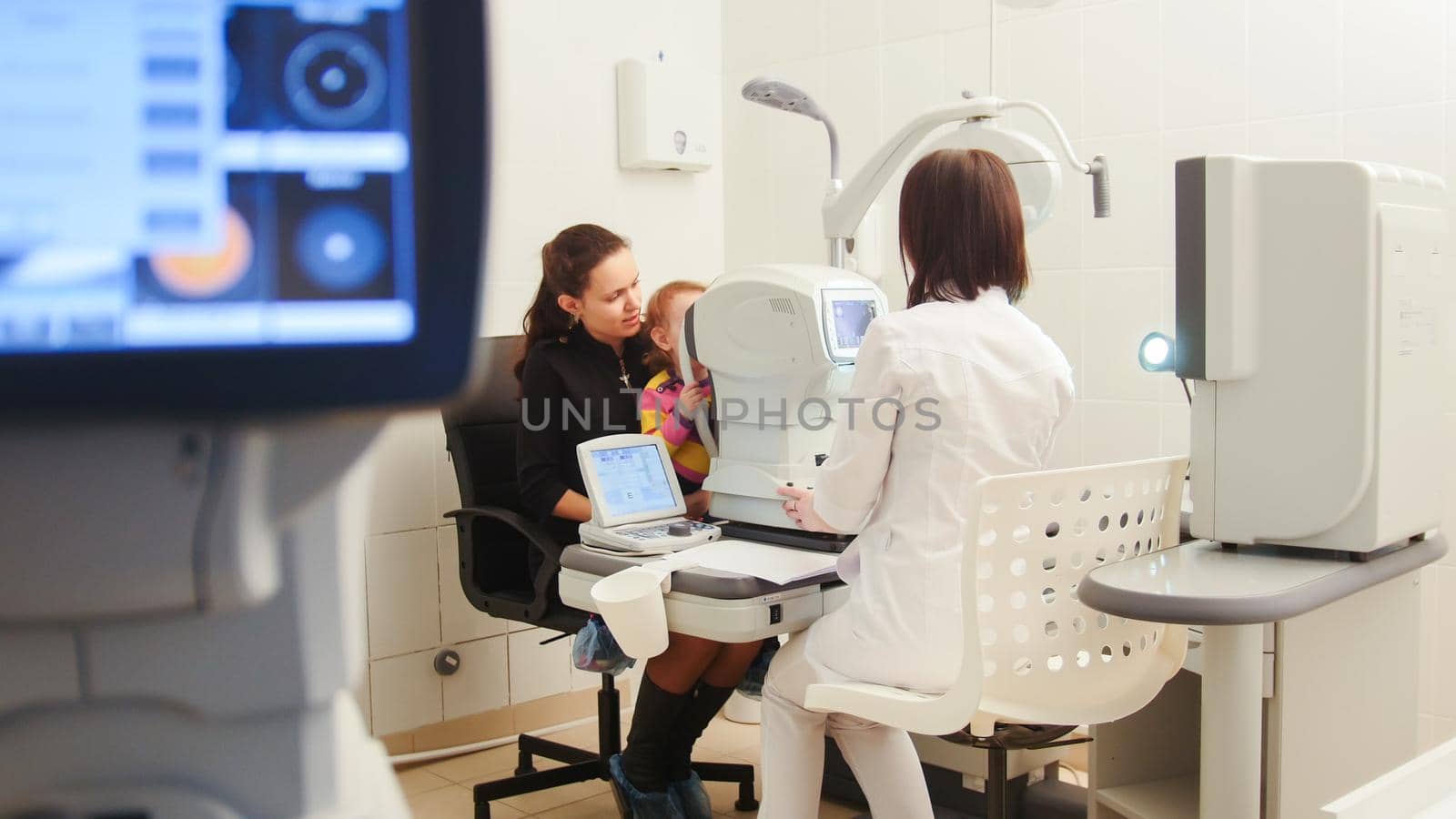 Optometrist in clinic checking little child's vision, wide angle