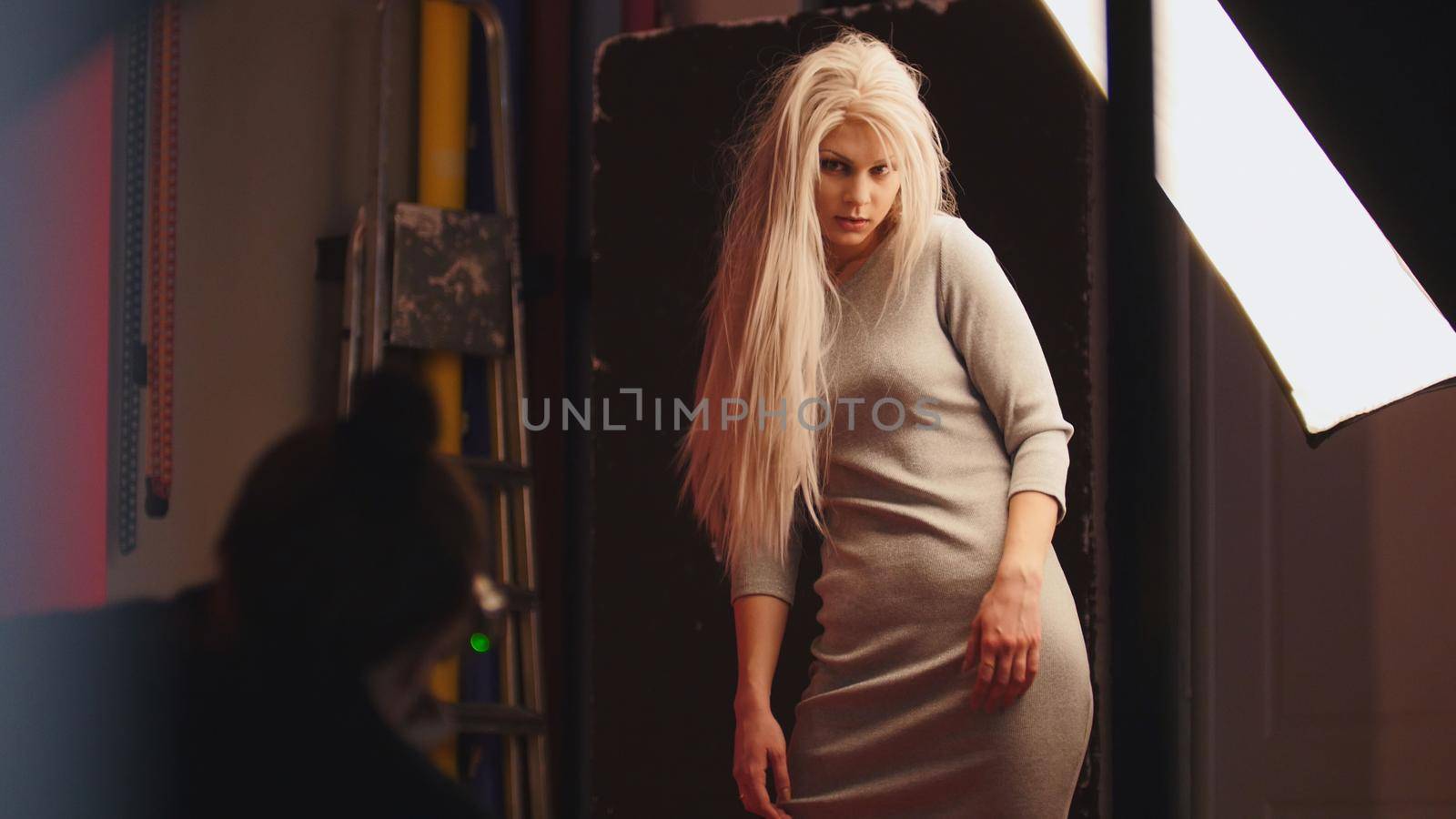 Sensual blonde caucasian blonde female model posing for photographer - fashion backstage, telephoto