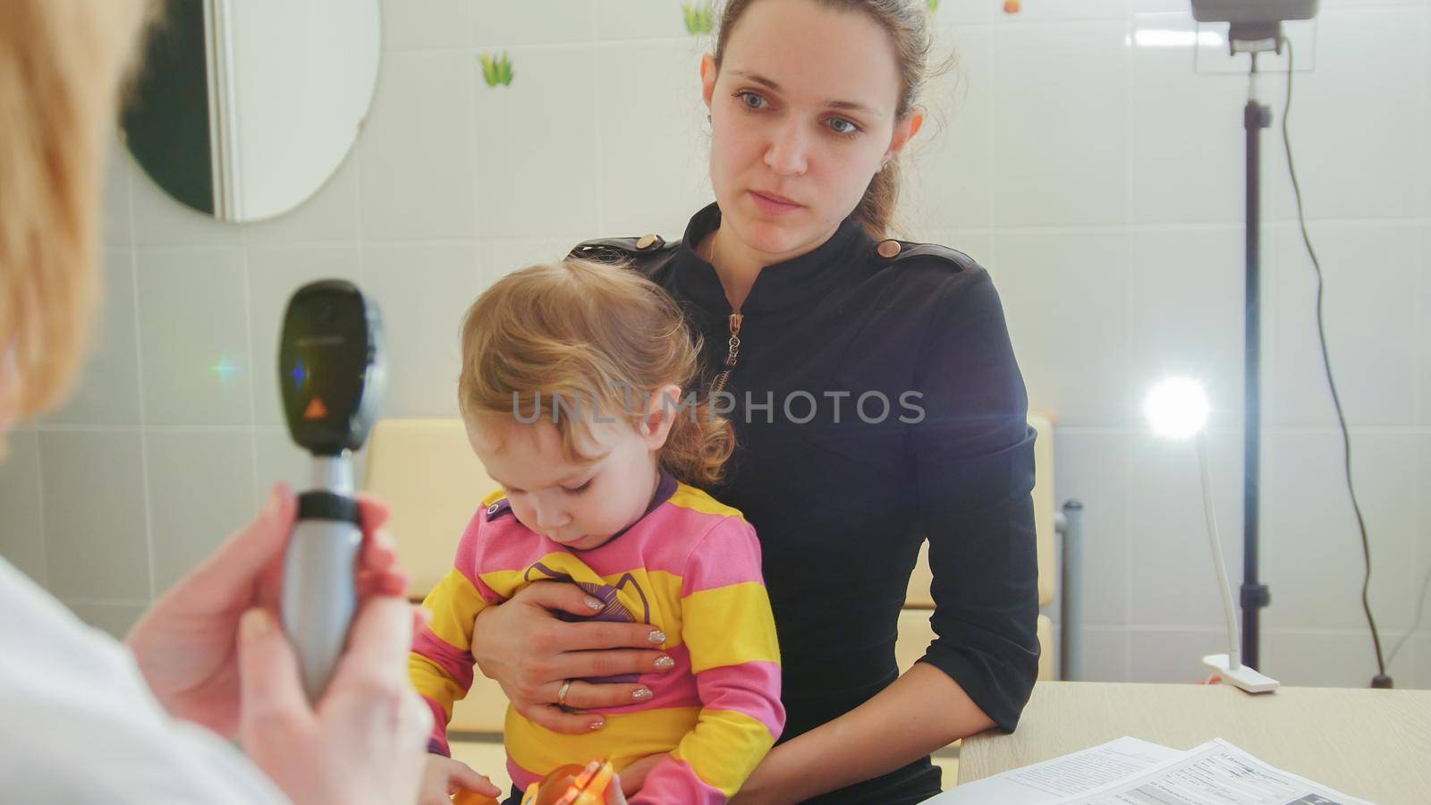 Ophthalmology - doctor gives consultations to the mother of the girl about eyesight of little girl - child's healthcare, telephoto