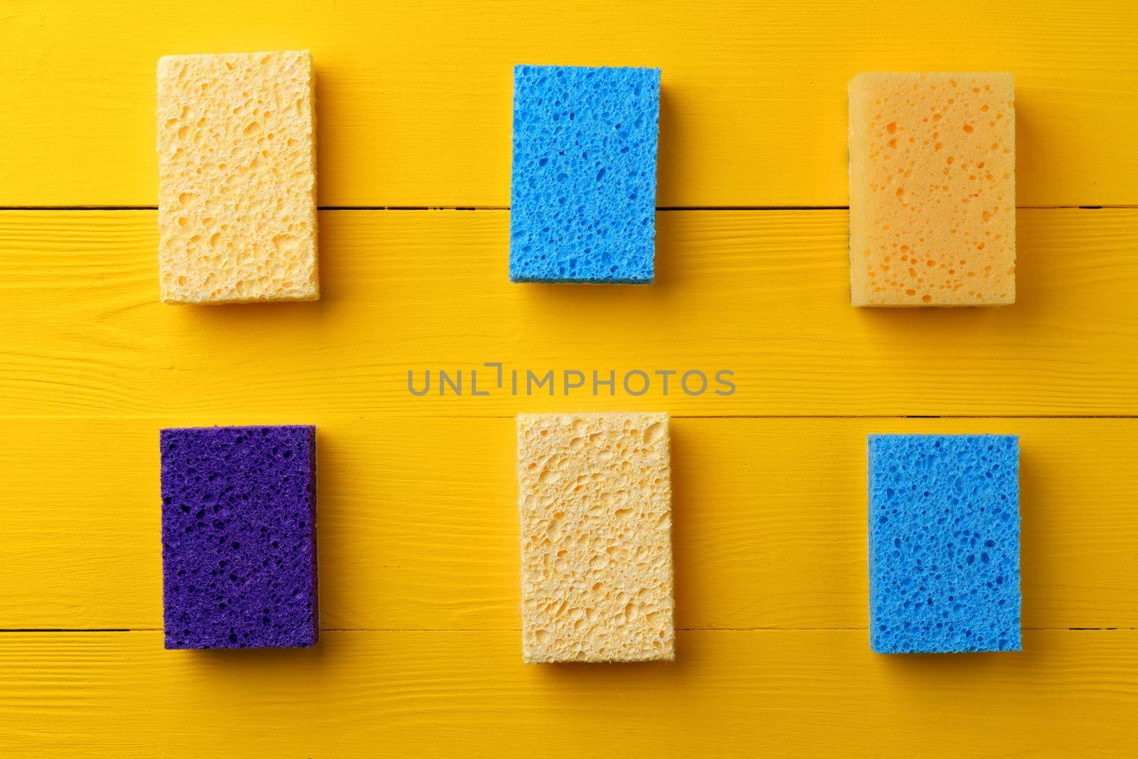 Cleaning sponges on yellow wooden background flat lay top view