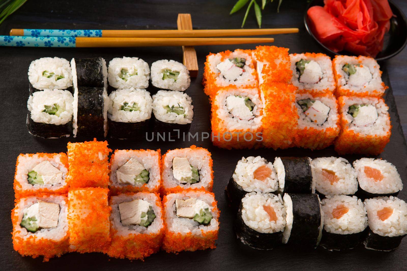 Set of sushi rolls with wasabi and ginger on a black background. Japanese oriental cuisine .