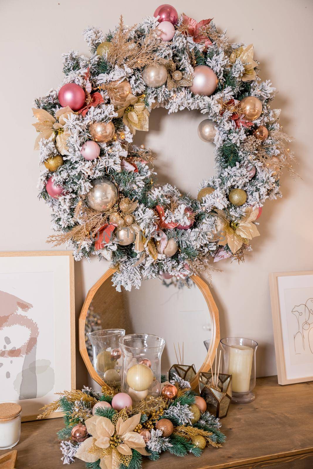 Christmas wreath made of natural fir branches hanging on a white wall. Wreath with natural ornaments: bumps, walnuts, cinnamon, cones.
