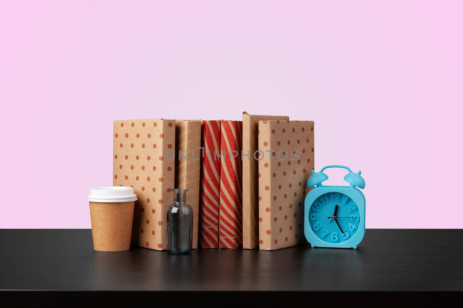 Education concept with stack of books on a table against colored background, front view