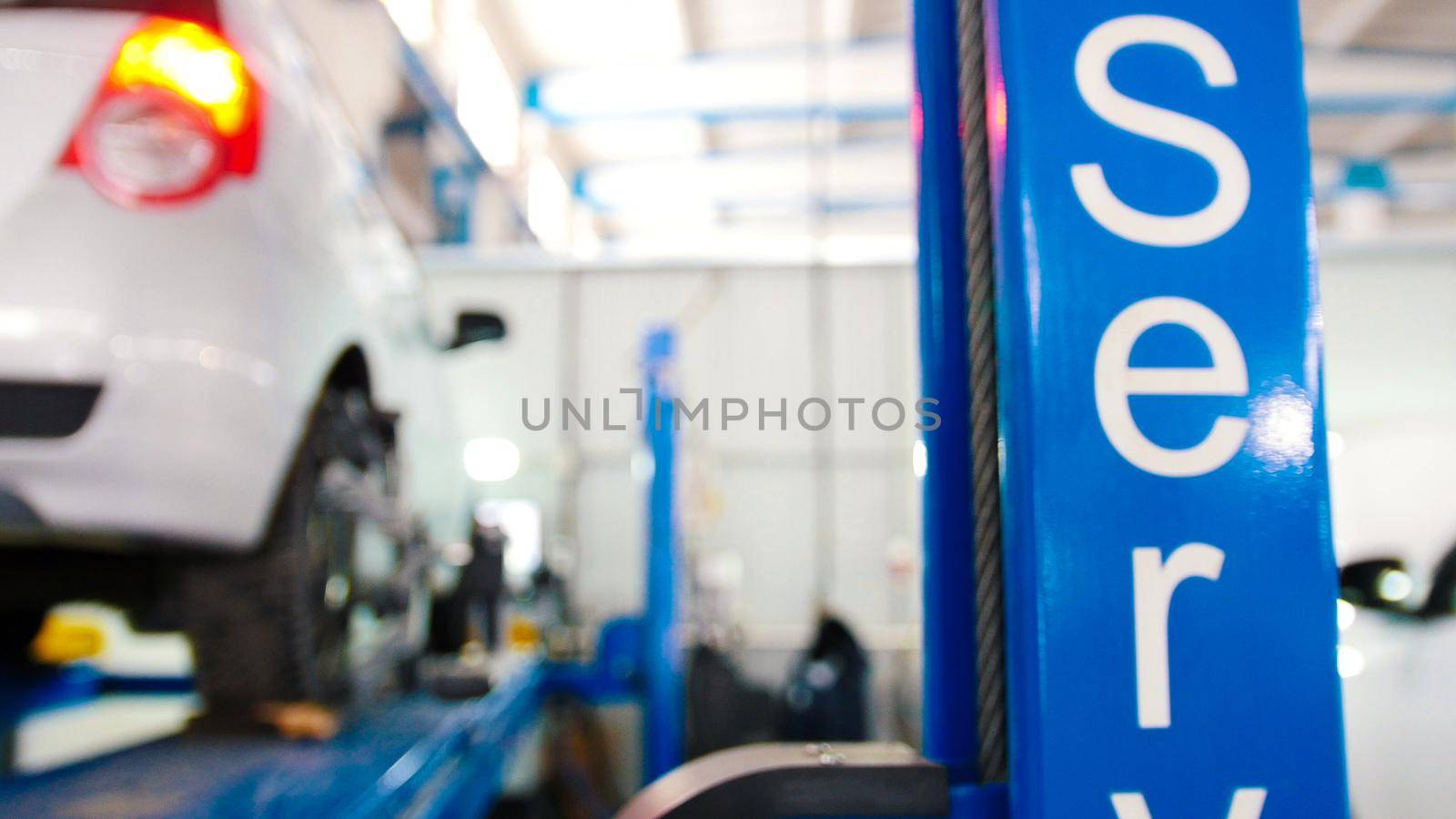 Lifted car in professional car service - the collapse of convergence - process repairing, defocused background, wide angle