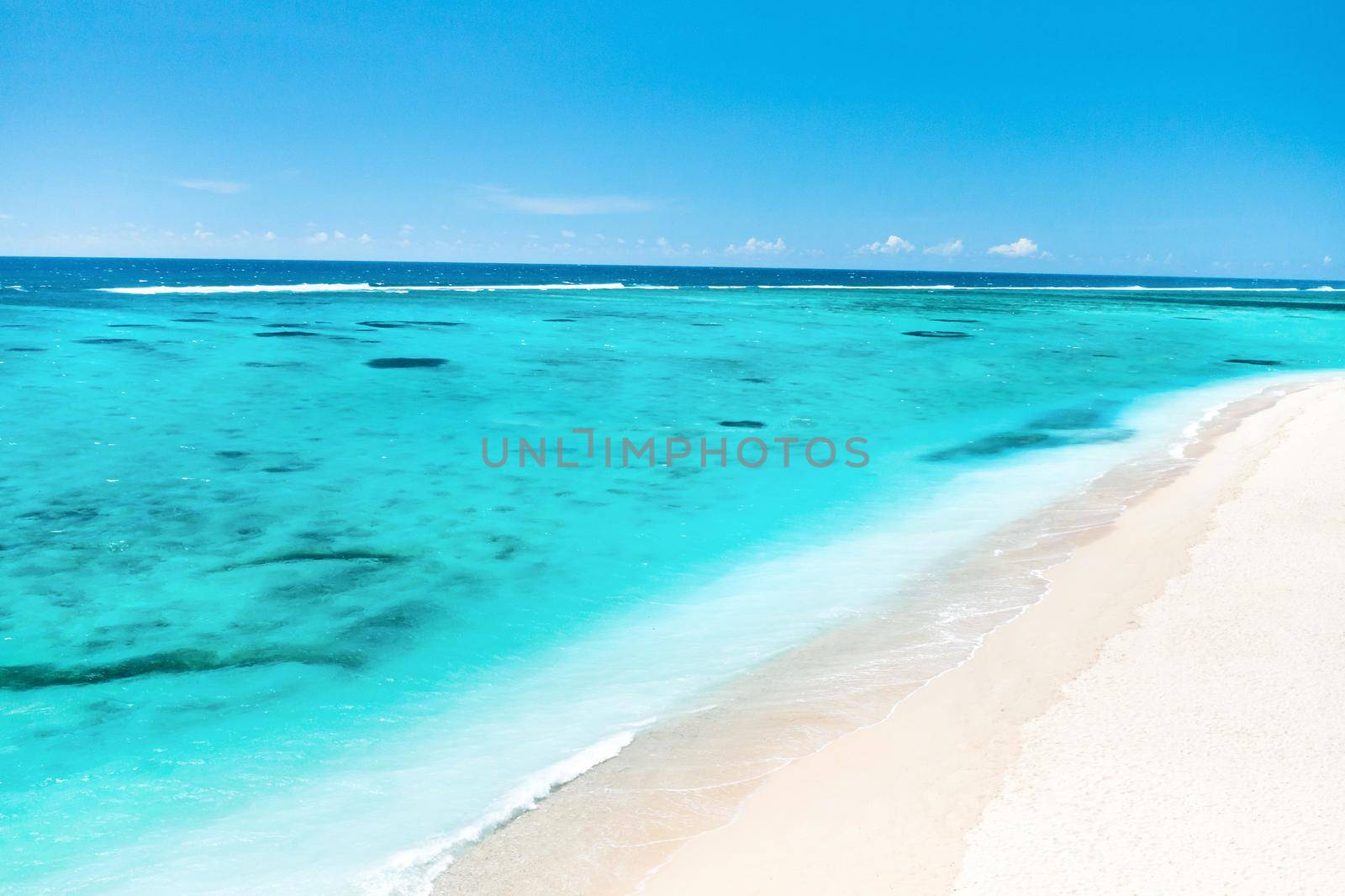 A view from a height of a Tropical beach and waves breaking on a tropical golden sandy beach. The sea waves gently wind along the beautiful sandy beach by Lobachad