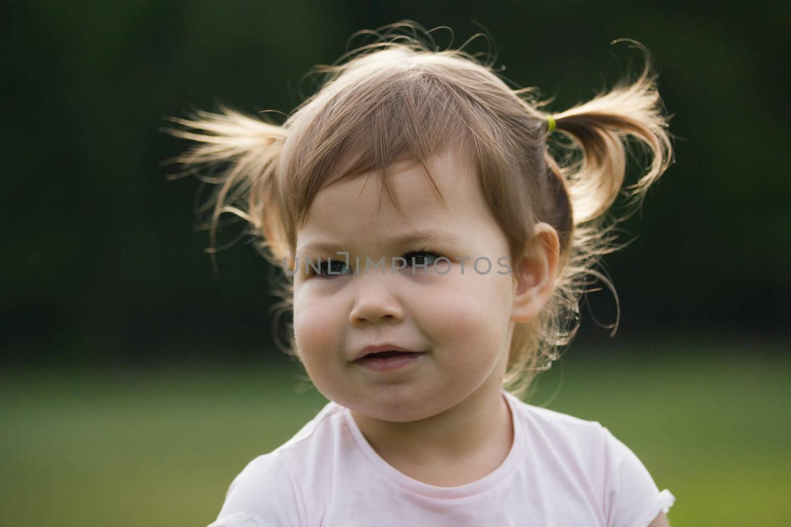 Little hild girl playing in park in front of green grass, portrait