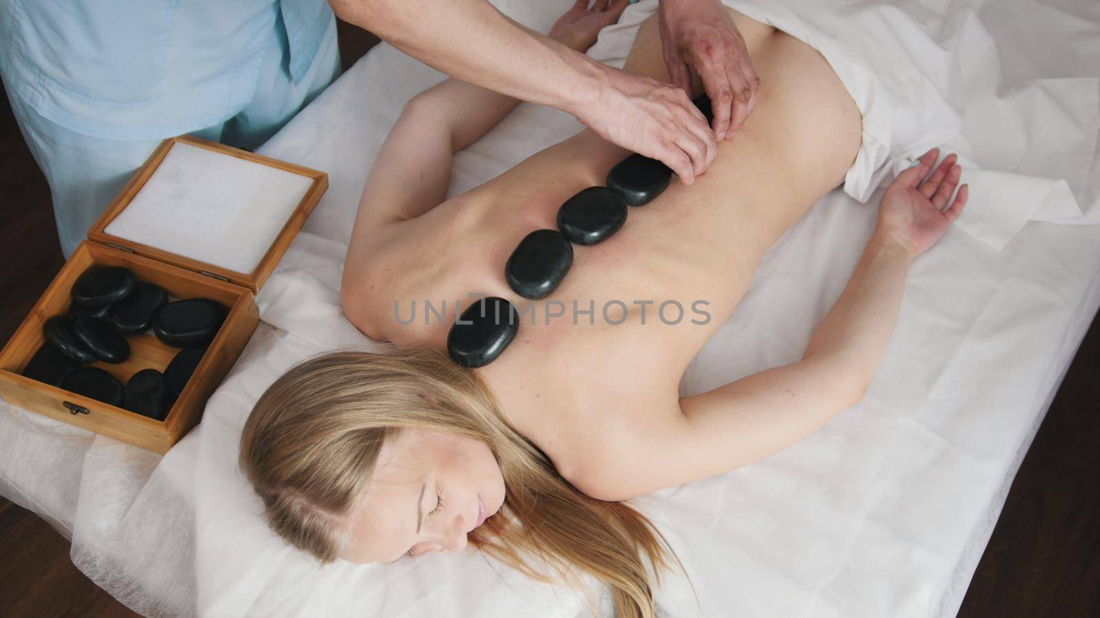 The clinic of Tibetan medicine. The doctor corrects stones for stone therapy on the back girl's