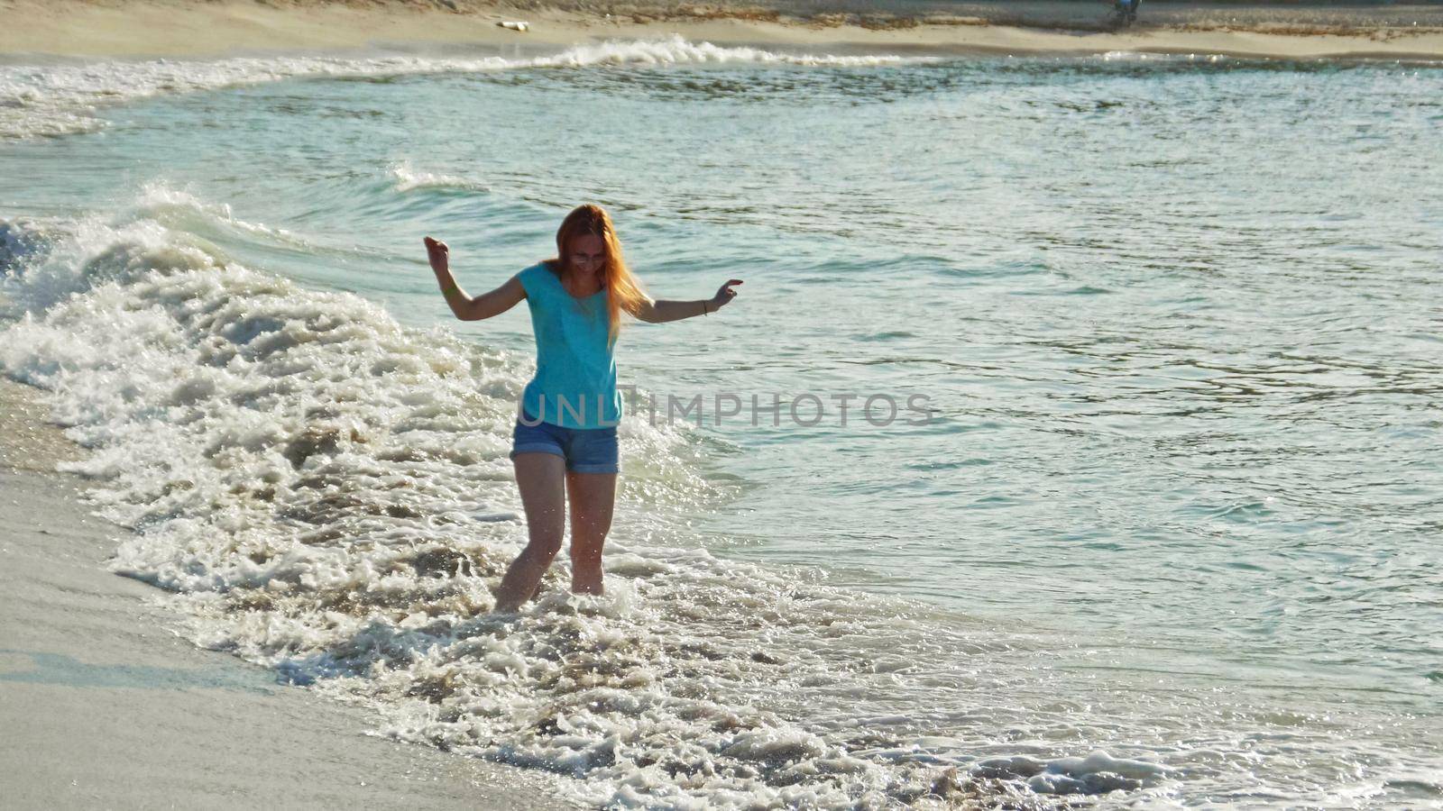 Young woman with long red hair play waves, seascape beach of Dominican Republic, Caribbean sea