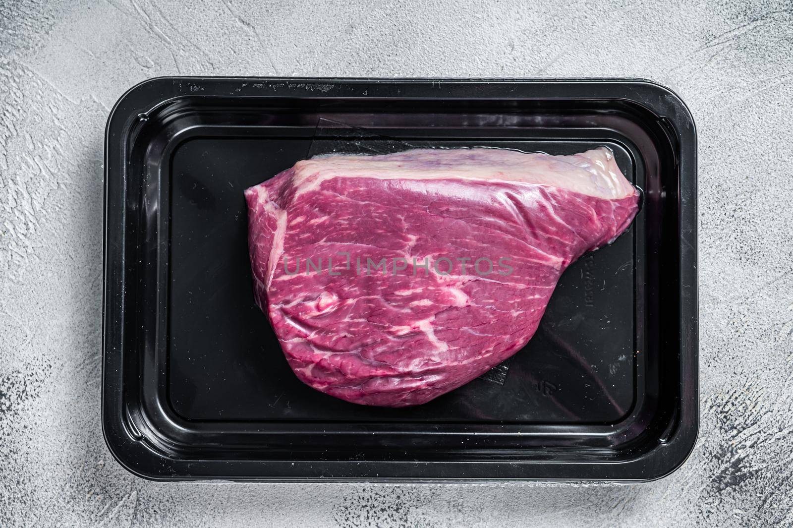 Raw cap rump steak or top sirloin beef meat steak in vacuum packaging. White background. Top view.