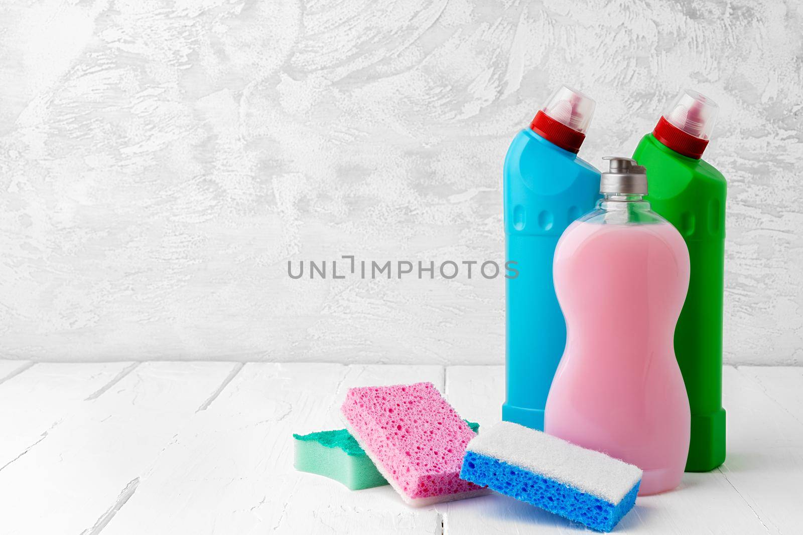 Household cleaning detergents on wooden table against gray background, close up