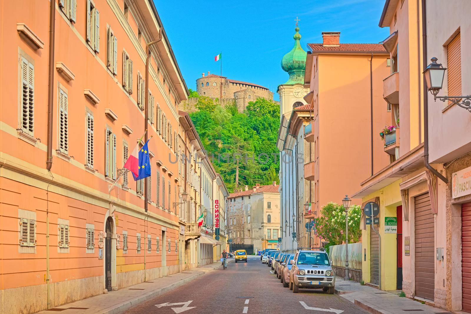 Gorizia - June 2020, Italy: A street with vivid orange buildings, parked cars and a man on a bike