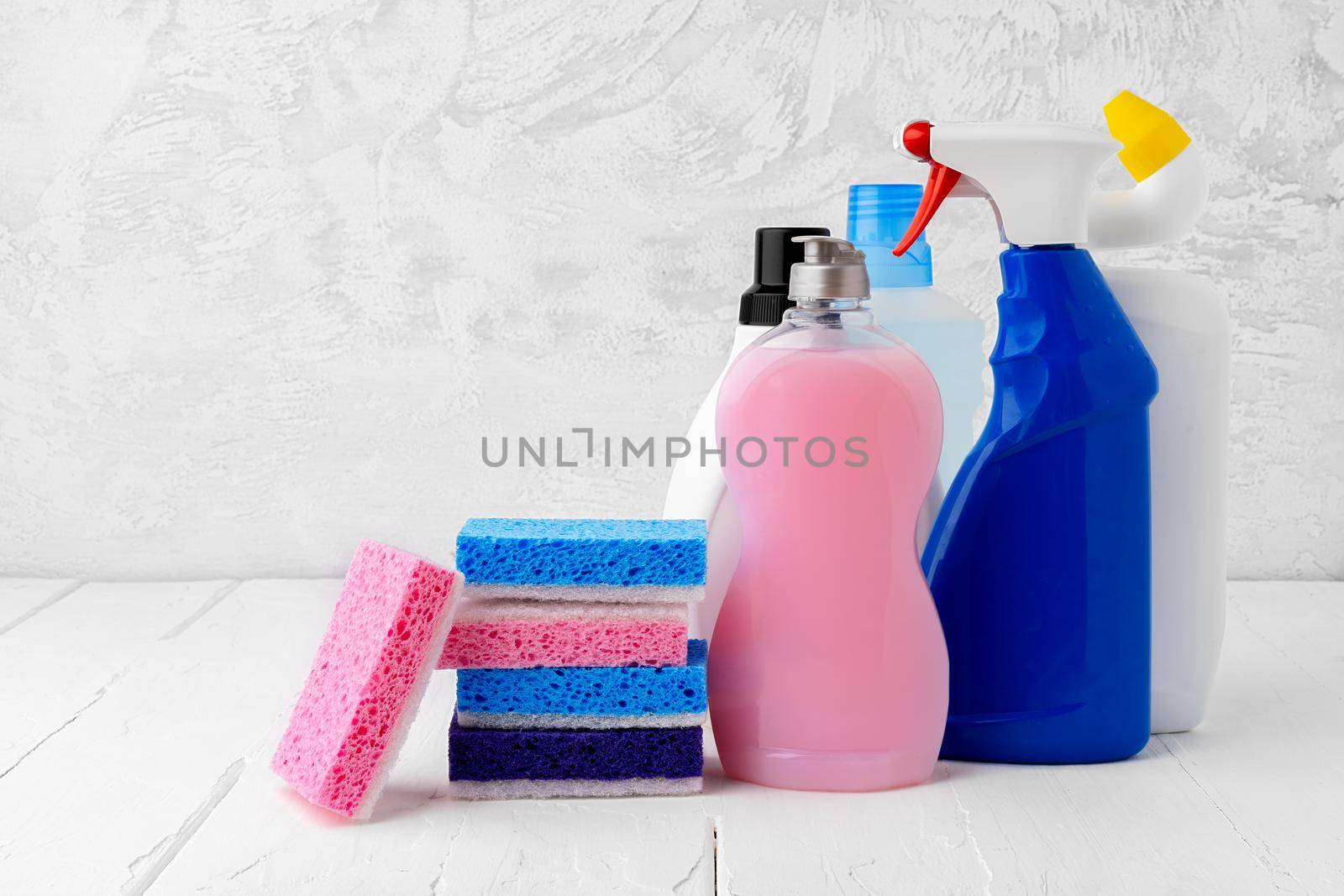 Household cleaning detergents on wooden table against gray background, close up