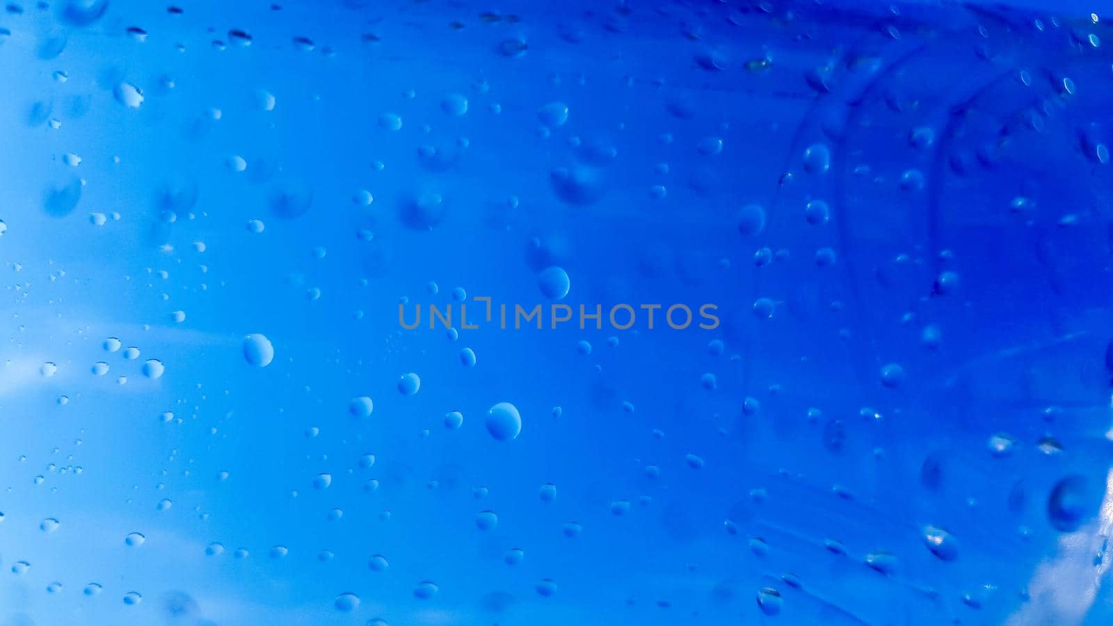 A lot of drops of water inside a plastic bottle. Blue background with water drops.
