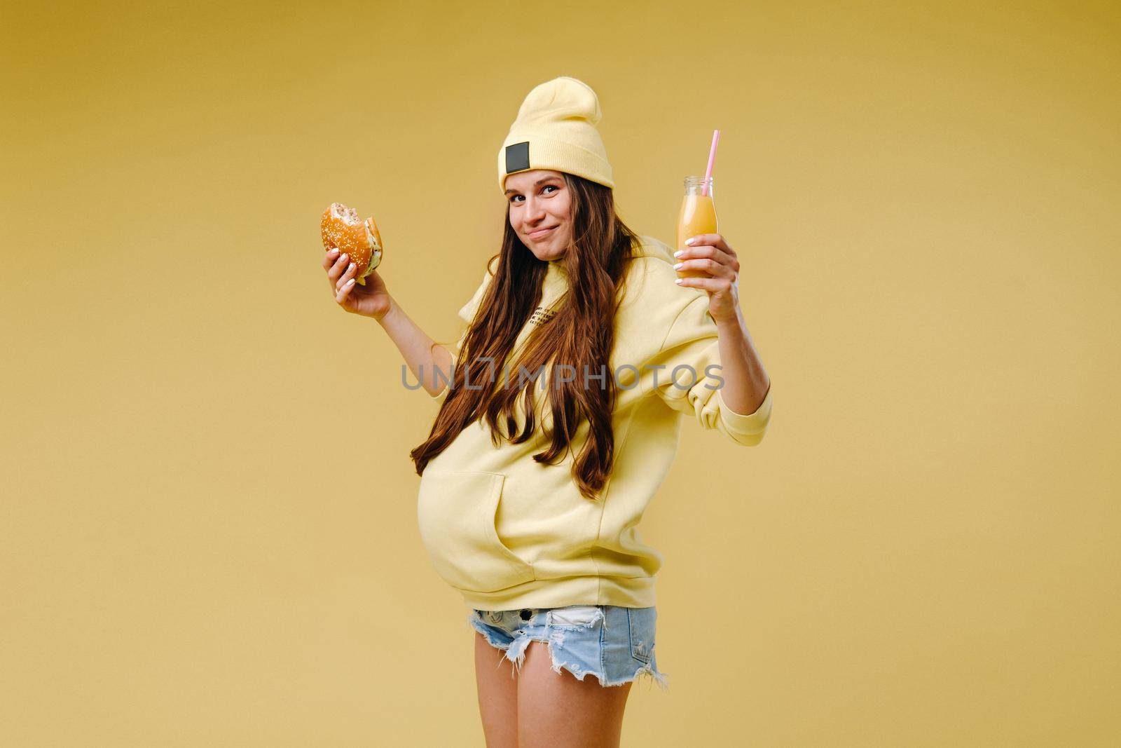 pregnant girl in yellow clothes with hamburgers in her hands on a yellow background by Lobachad