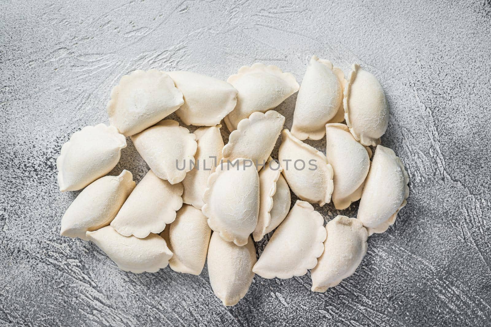 Raw frozen dumplings pierogi on a kitchen table. White background. Top View. Copy space.