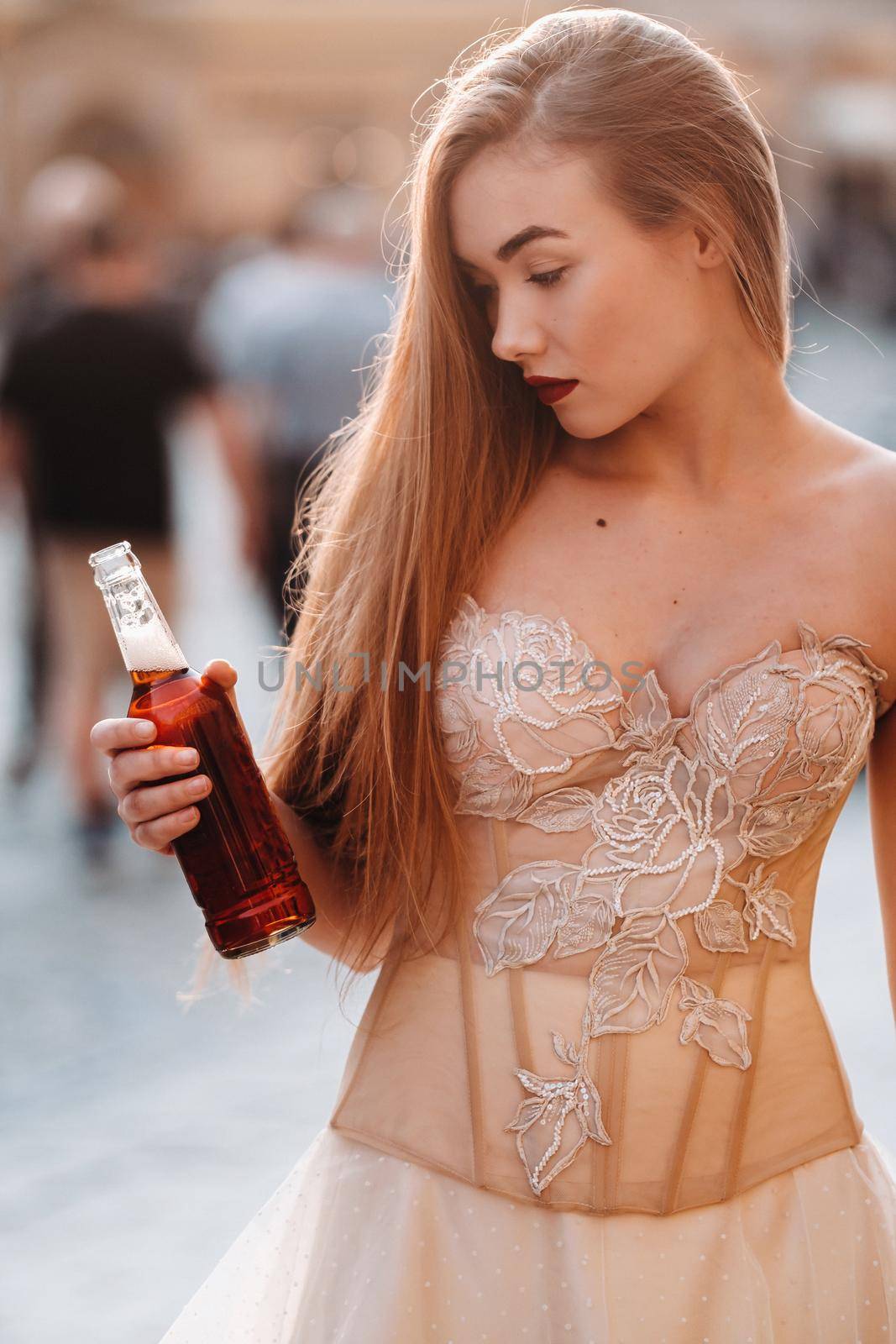 A bride in a wedding dress with long hair and a drink bottle in the Old town of Wroclaw. Wedding photo shoot in the center of an old Polish city.Wroclaw, Poland by Lobachad