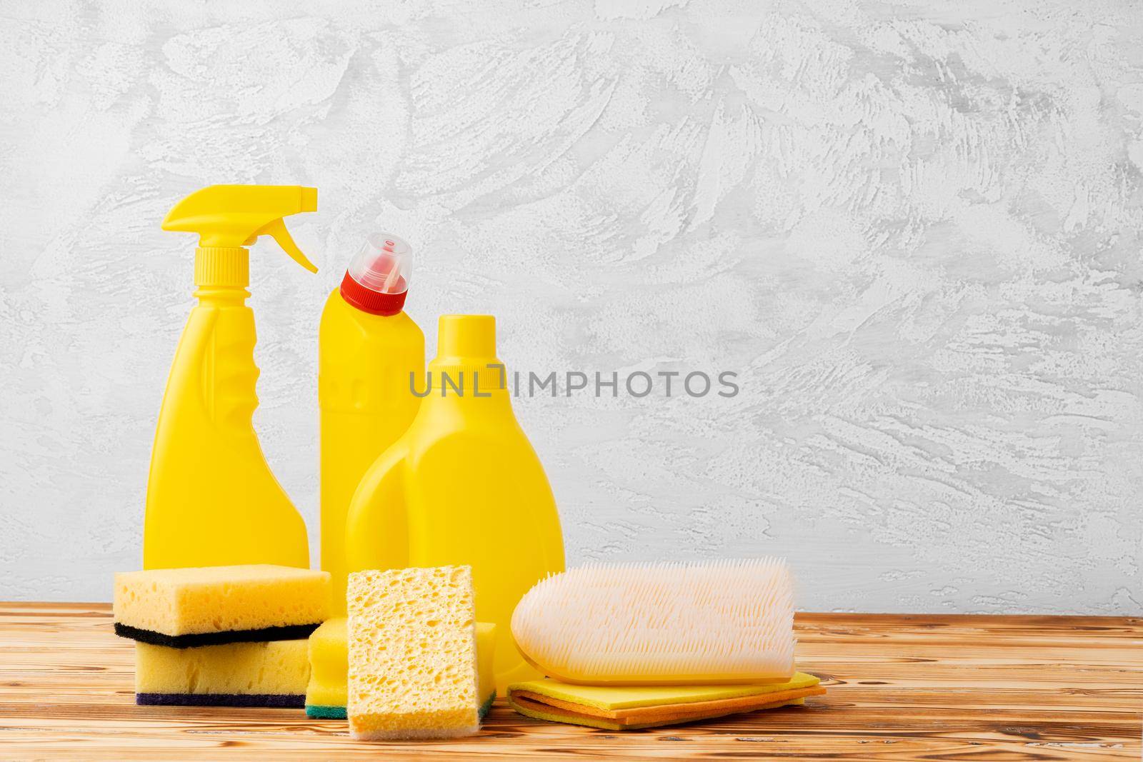 Household cleaning detergents on wooden table against gray background, close up