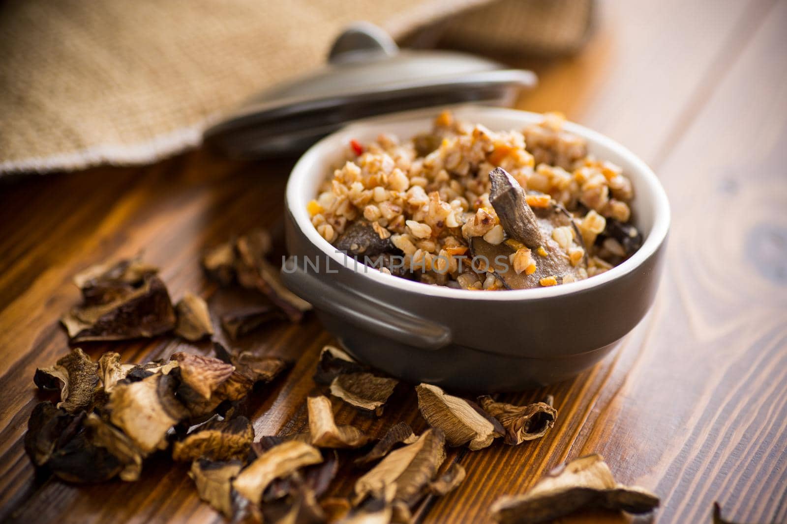 boiled buckwheat with organic forest dried mushrooms in a ceramic bowl on a wooden table