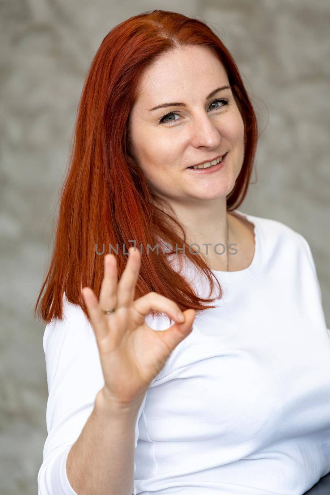 smiling woman with red hair showing her fingers approx. vertical photo portrait, close up
