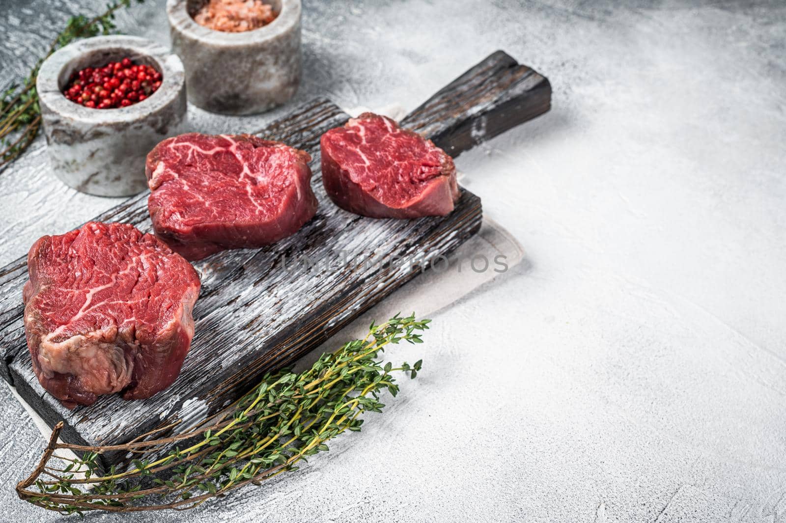 Fillet mignon beef raw steaks on a wooden board with salt and pepper. White background. Top view. Copy space by Composter