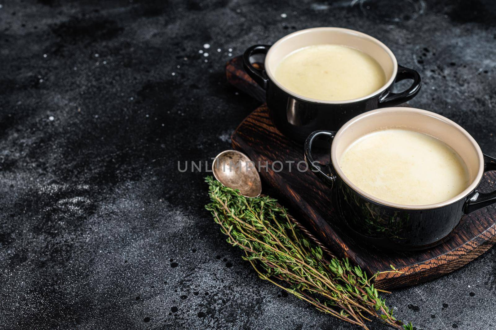 Potato cream soup in bowls on kitchen table. Black background. Top view. Copy space.