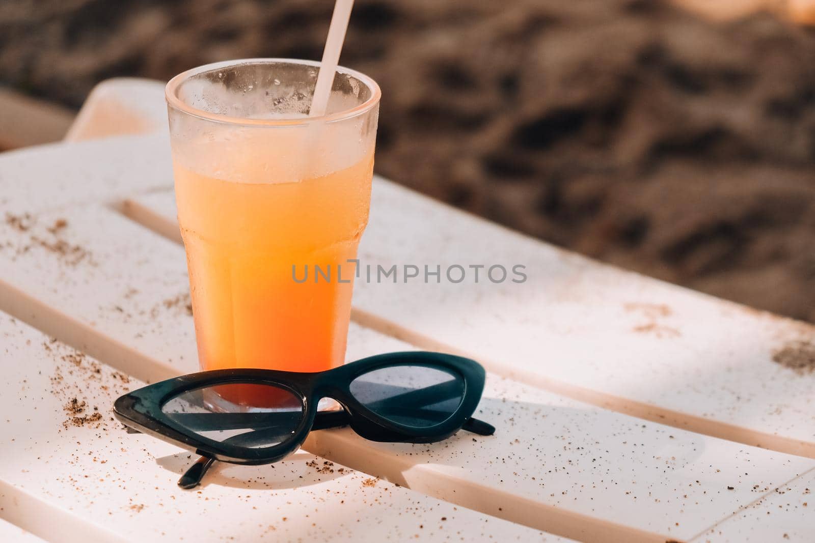 Fresh cold mango smoothie cocktail on tropical beach bright sand. Summer sea vacation and travel concept. Glass of fruit cocktail and sunglasses. Summertime vacation