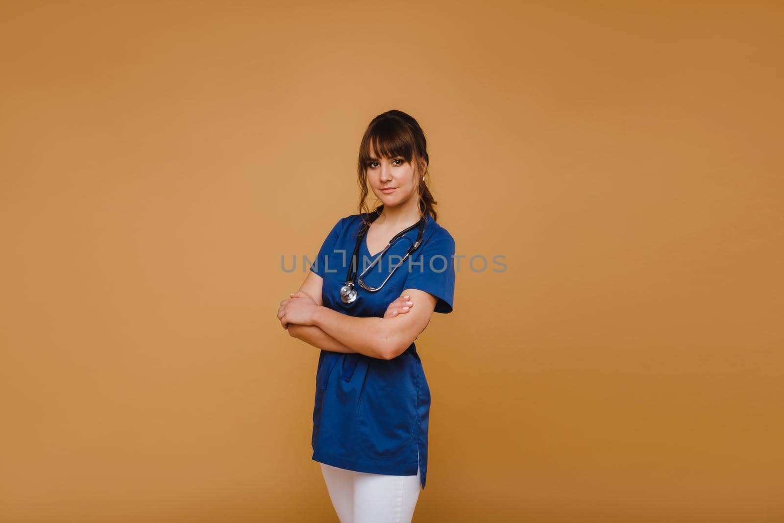 Cheerful happy doctor with arms crossed on a brown background,