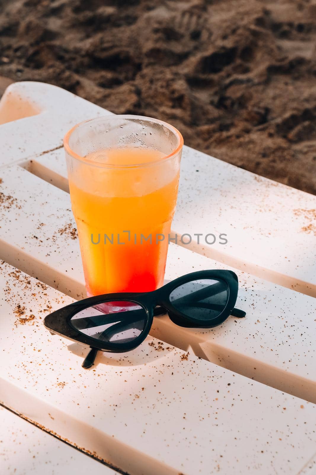 Fresh cold mango smoothie cocktail on tropical beach bright sand. Summer sea vacation and travel concept. Glass of fruit cocktail and sunglasses. Summertime vacation
