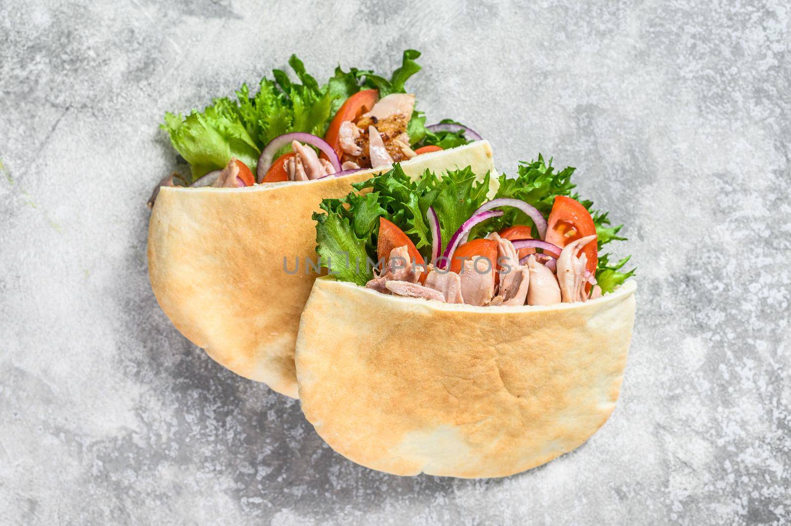 Doner kebab with grilled chicken meat and vegetables in pita bread. Gray background. Top view.