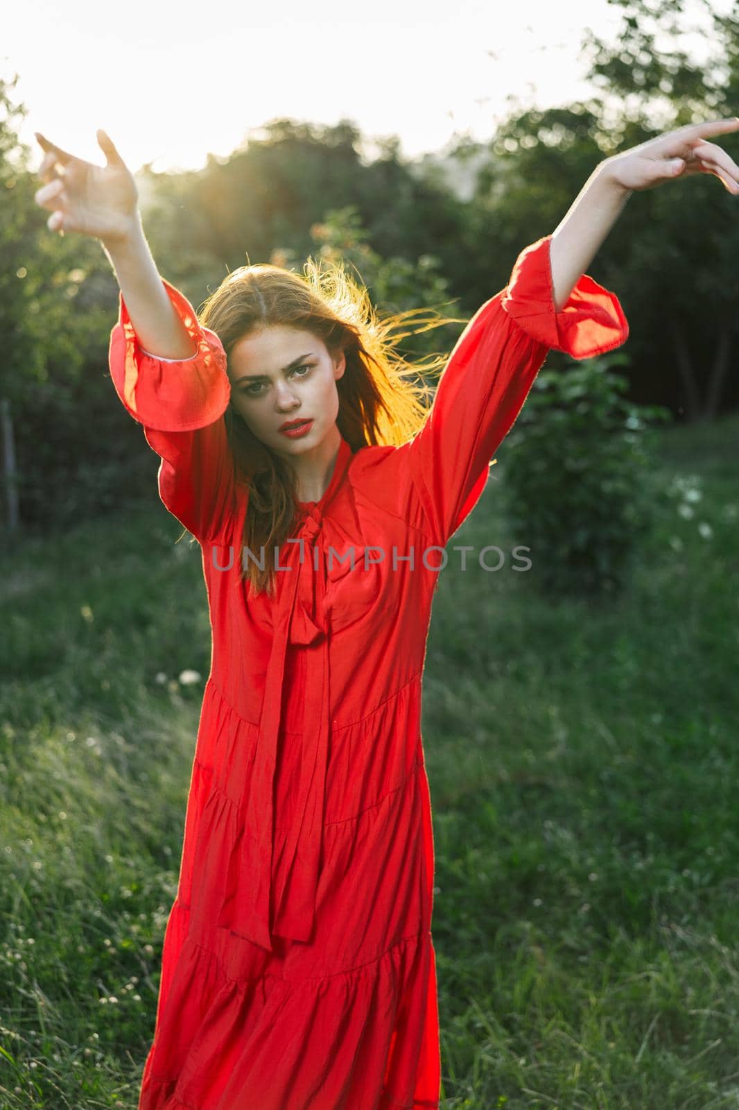 attractive woman in red dress posing in nature green grass. High quality photo