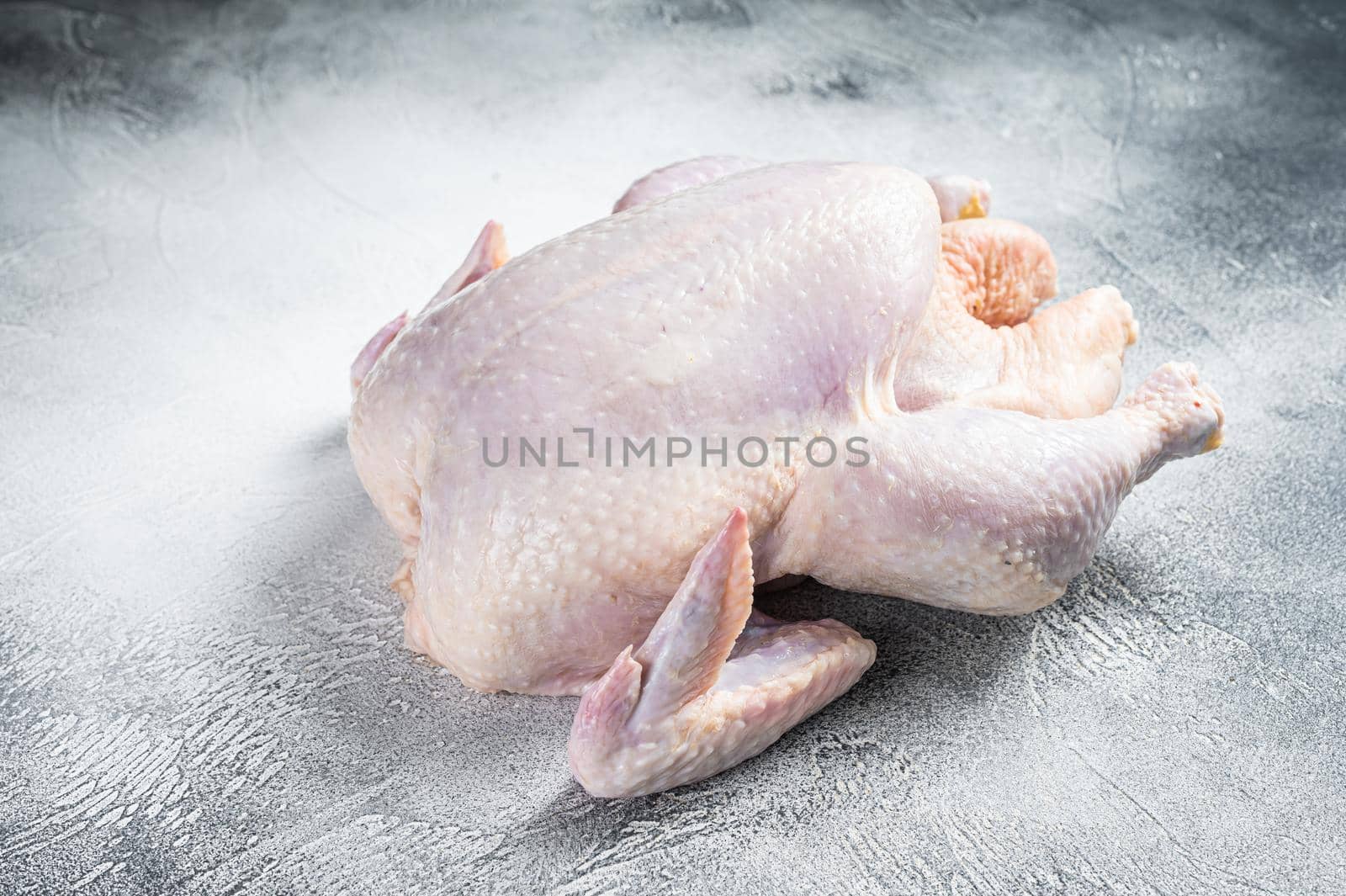 Raw free range whole chicken on a kitchen table. White background. Top view.