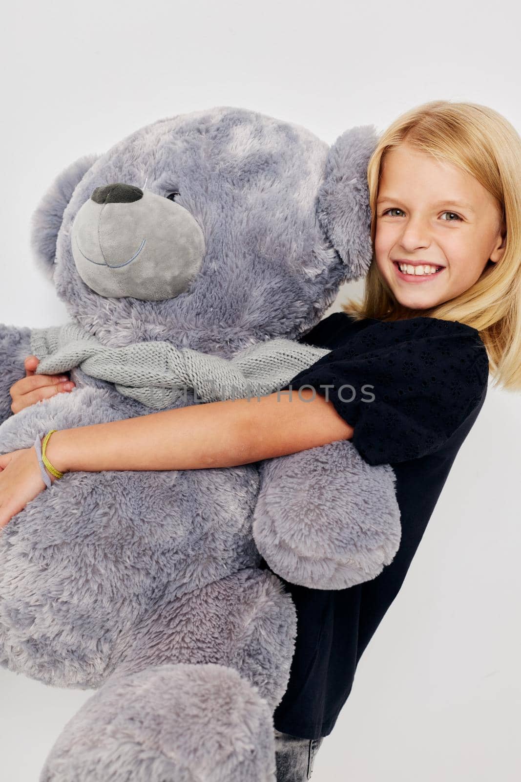 Positive little girl teddy bear in the hands of fun on a light background. High quality photo