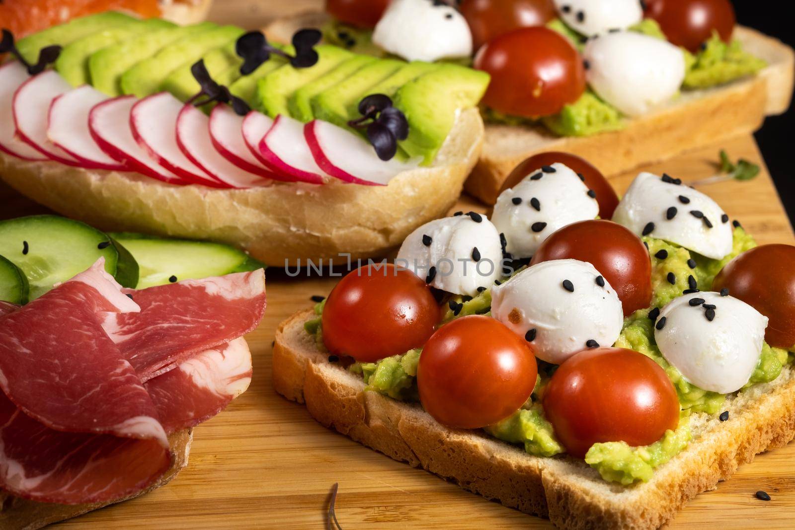 Assorted sandwiches with fish, cheese, meat and vegetables lying on the board.