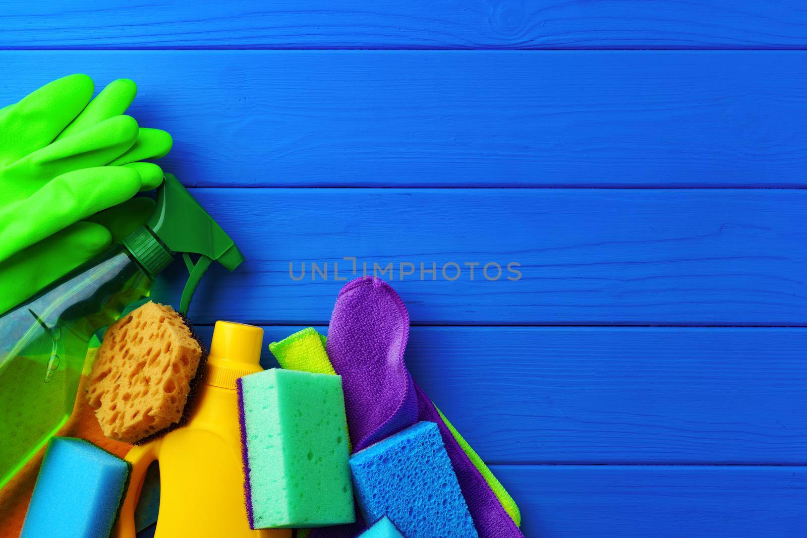 Household cleaning supplies on blue wooden background flat lay top view