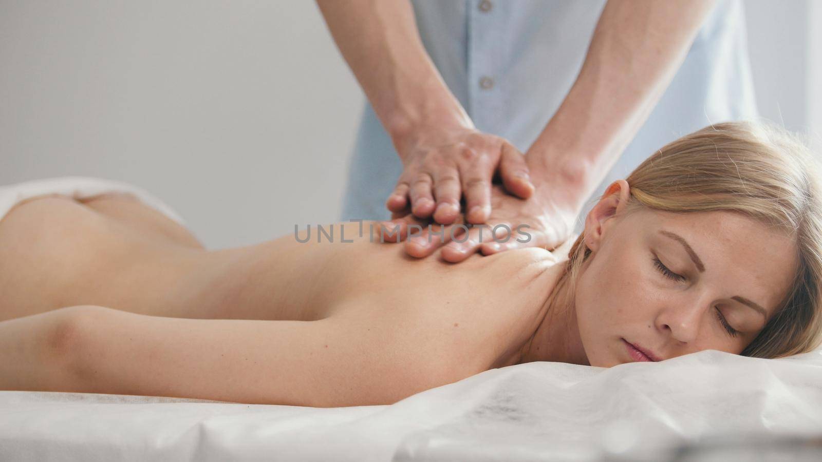 Spa. The male hands of the masseur make a massage on the hand of a young girl, top view