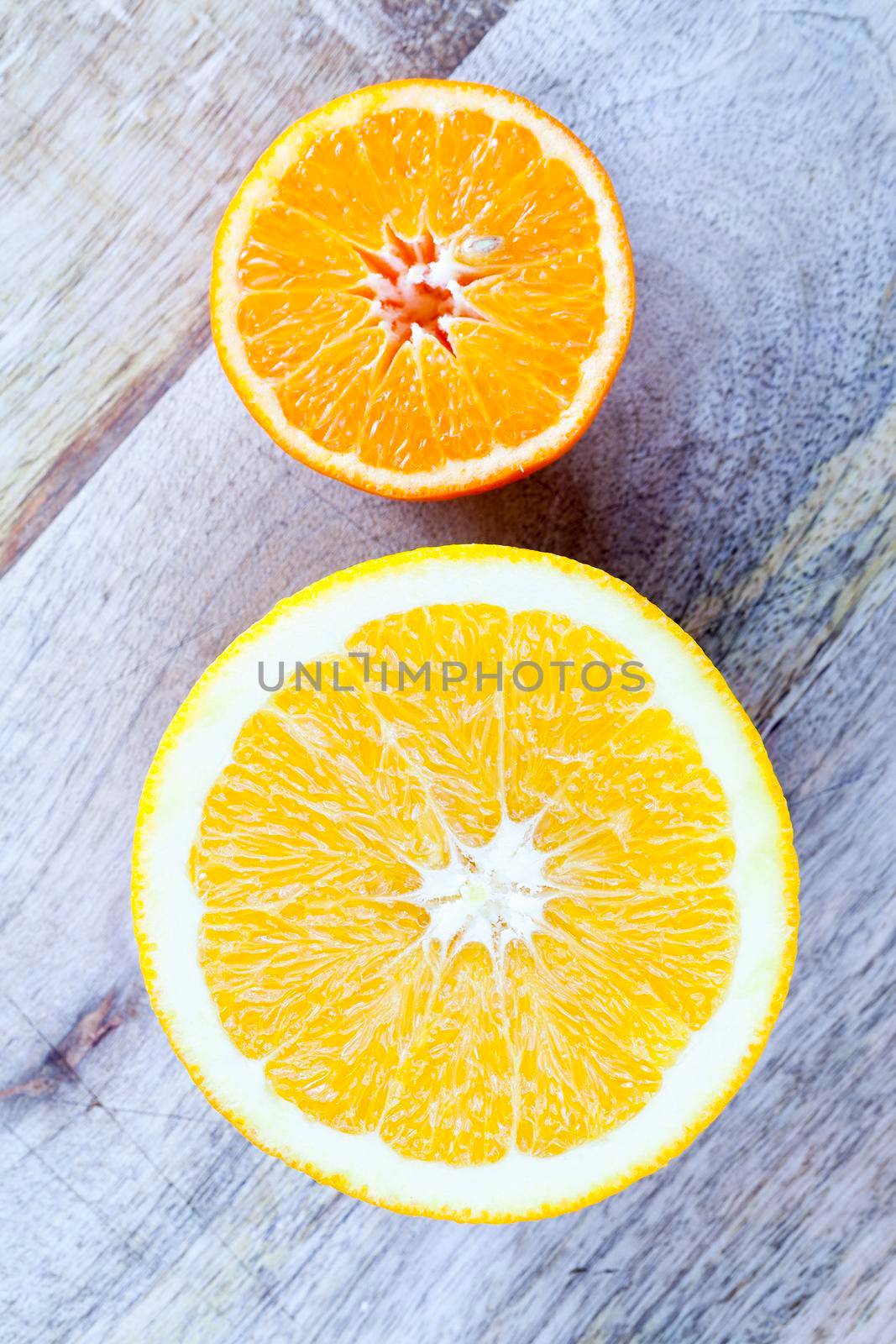 cut half orange and mandarin of different size without their bones, closeup of citrus on the board