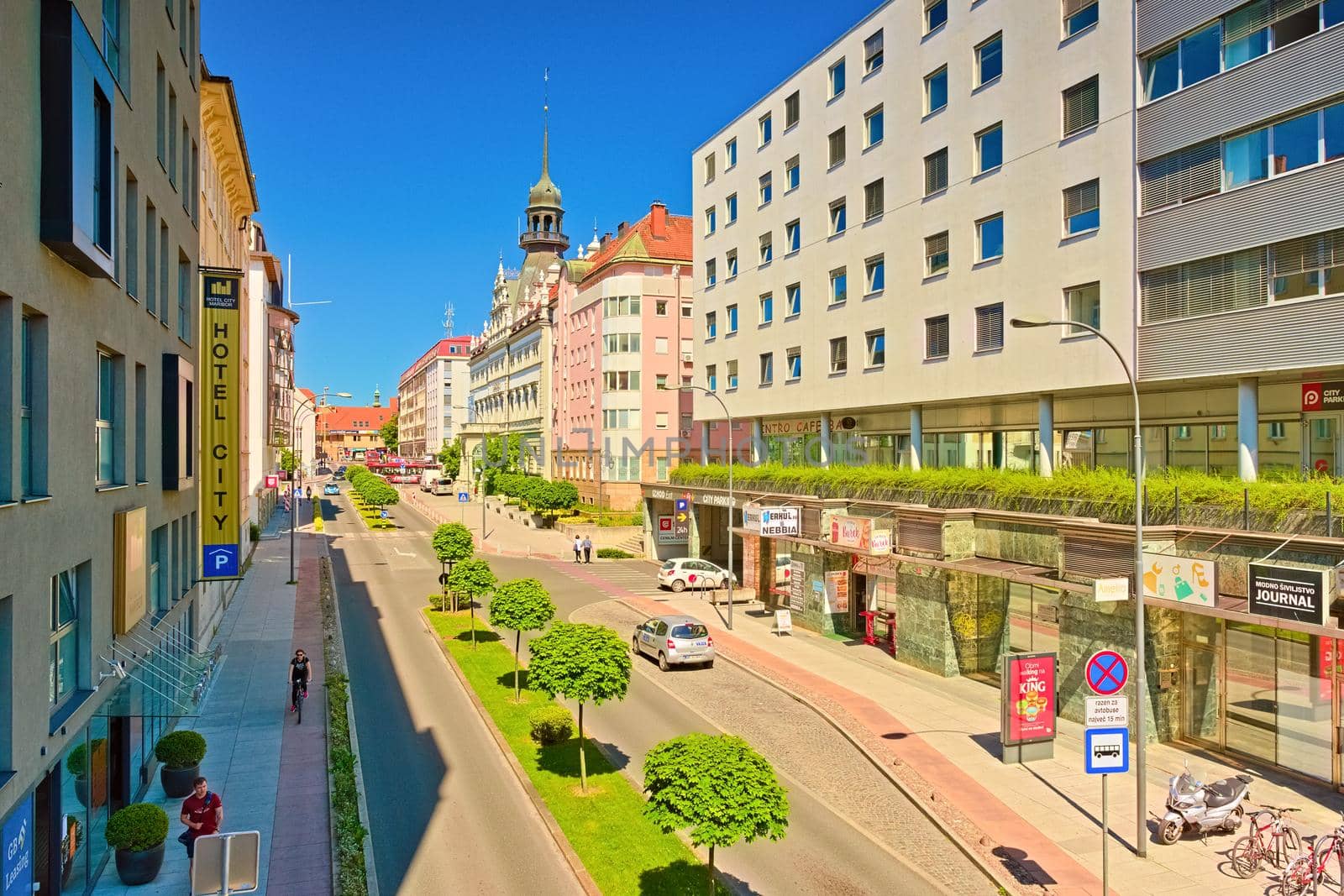 Maribor - June 2020, Slovenia: Street view with modern and old buildings, bus stop, shops, bars, a row of trees, and a hotel building (Ulica Kneza Koclja)