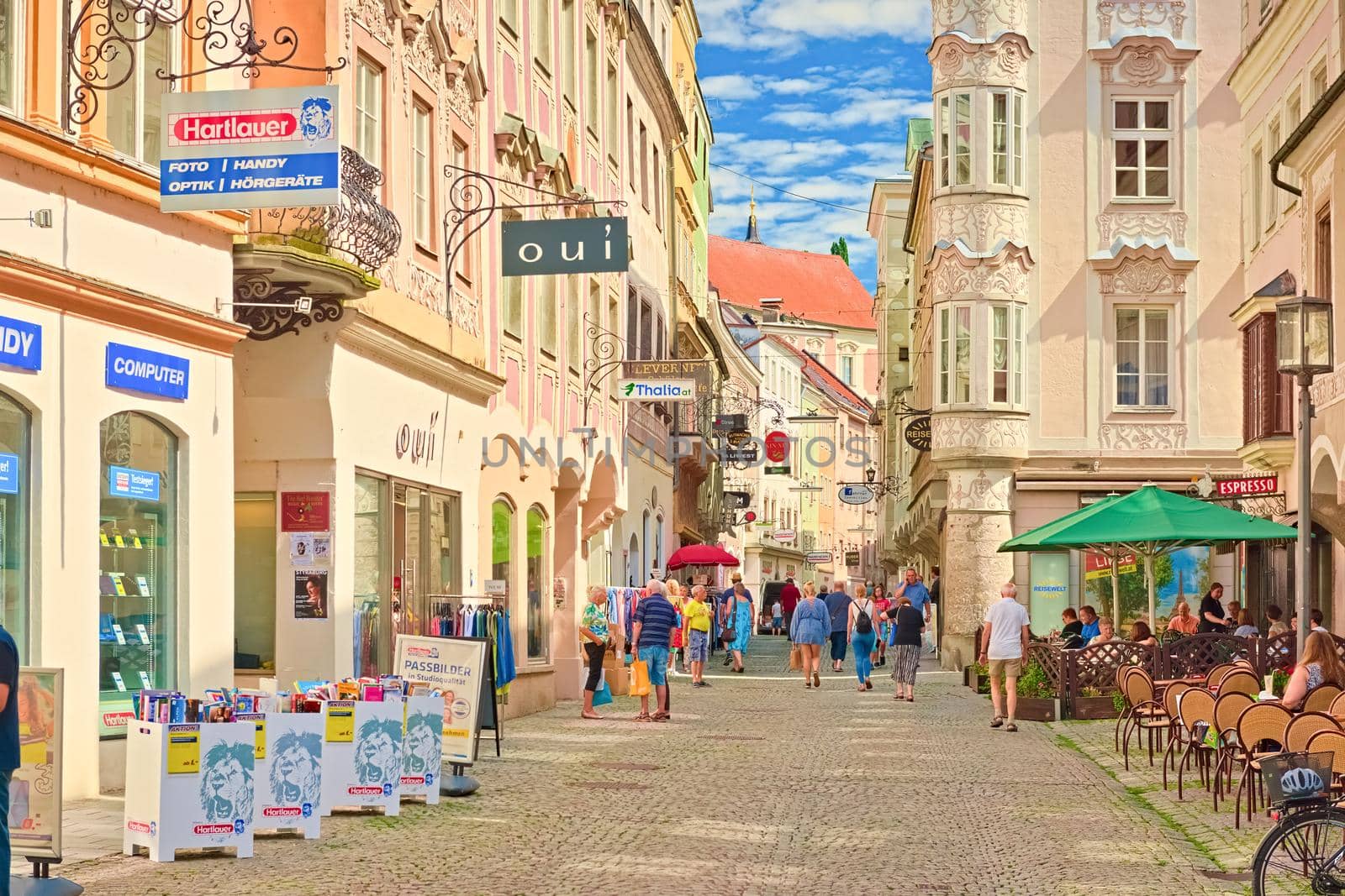 Steyr - June 2020, Austria: The main street with beautiful colorful buildings in the traditional architectural style and people sitting in the bar and strolling enjoying the beautiful day