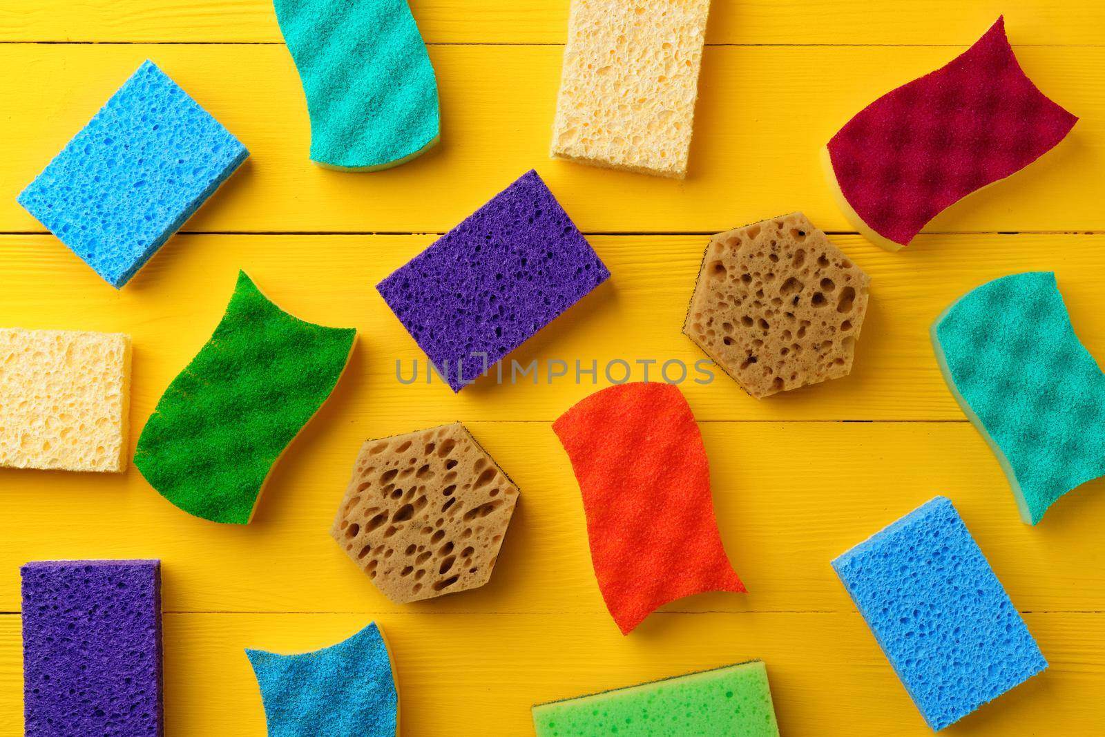 Cleaning sponges on yellow wooden background flat lay top view