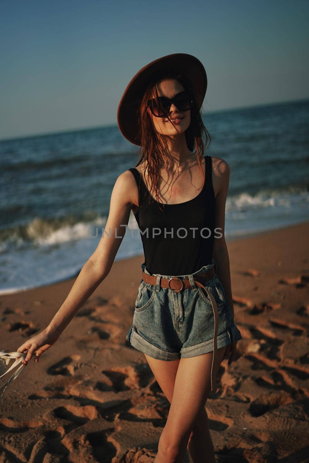 pretty woman in hat walking on the beach ocean travel. High quality photo