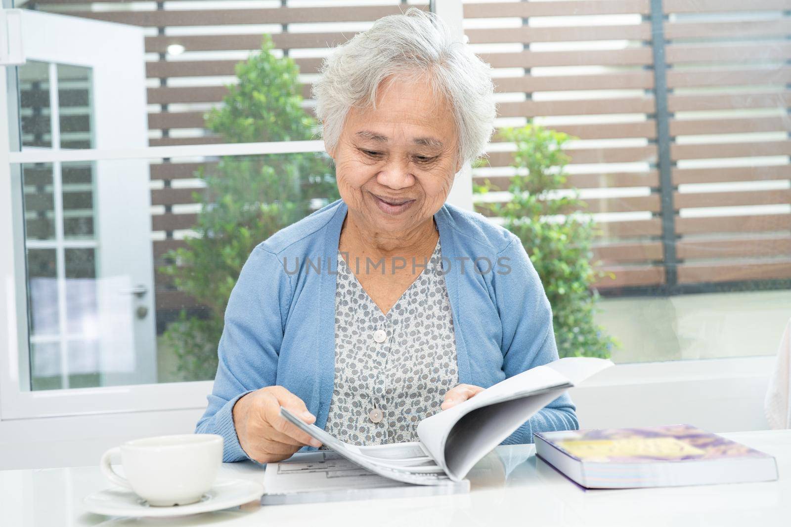Asian senior or elderly old lady woman reading a book for practice brain while living at home, resting hobby retirement concept.