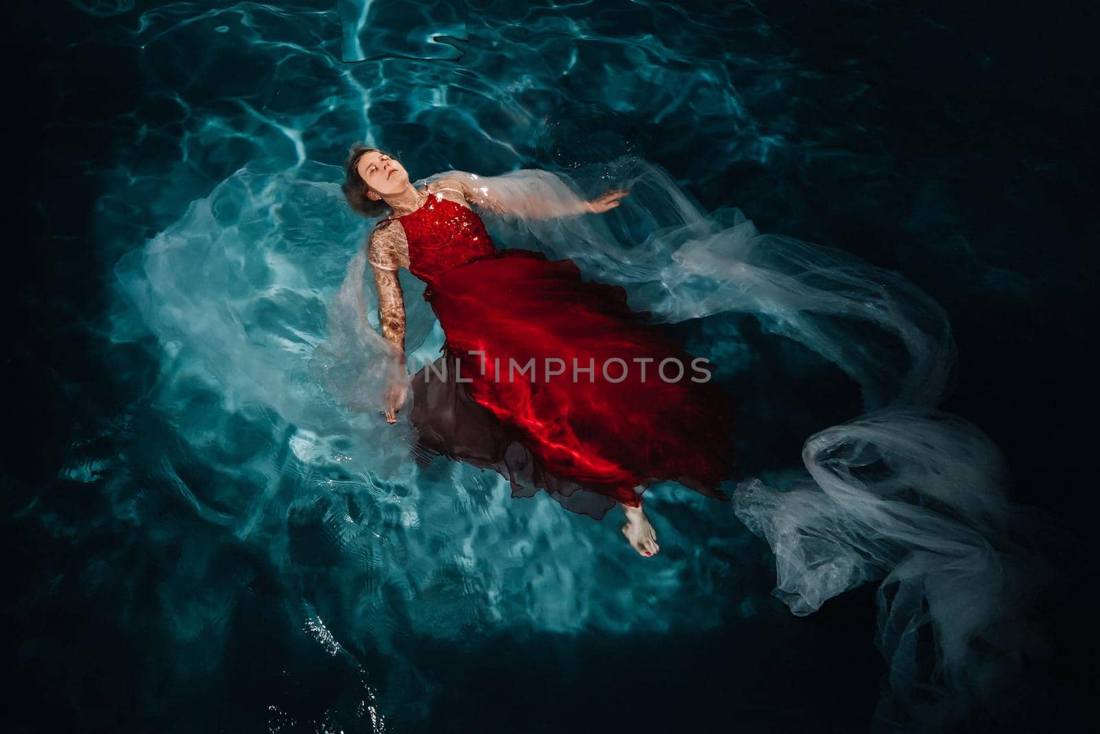 A girl in a red dress is floating on the water.A journey on the water of a single woman.