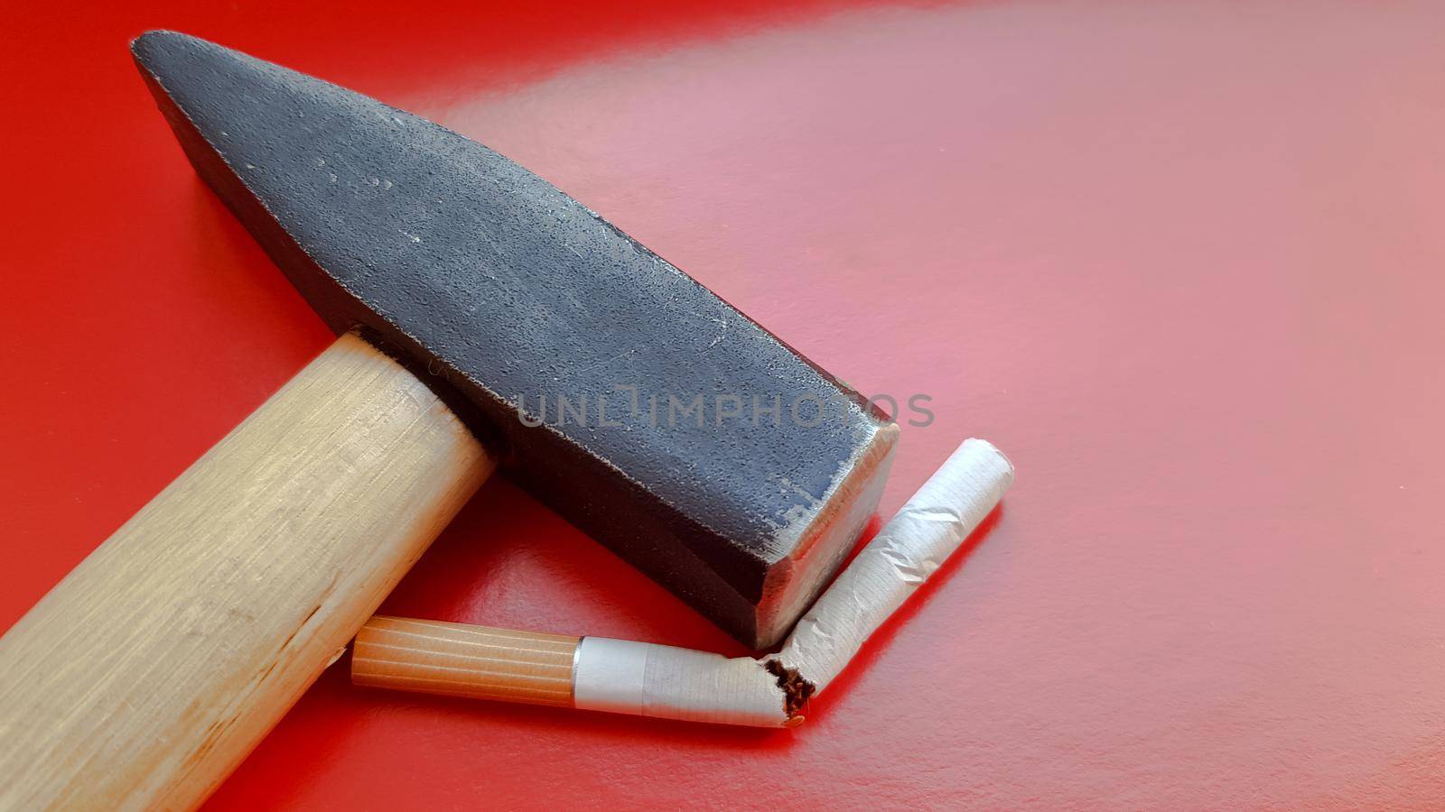 Hammer and a broken cigarette on a red background.