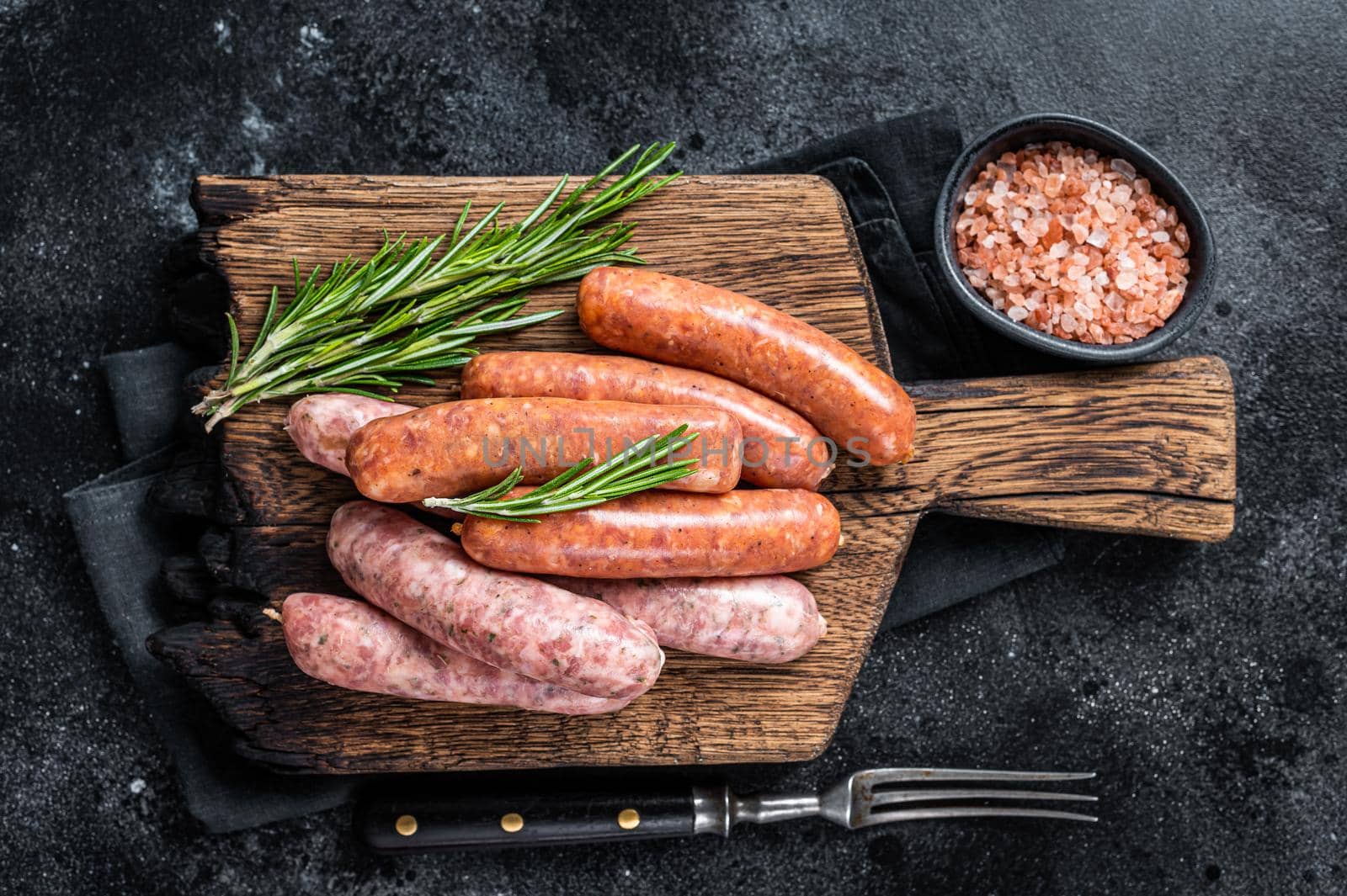 Uncooked Raw sausages Chorizo and Bratwurst with spices on wooden board. Black background. Top View by Composter