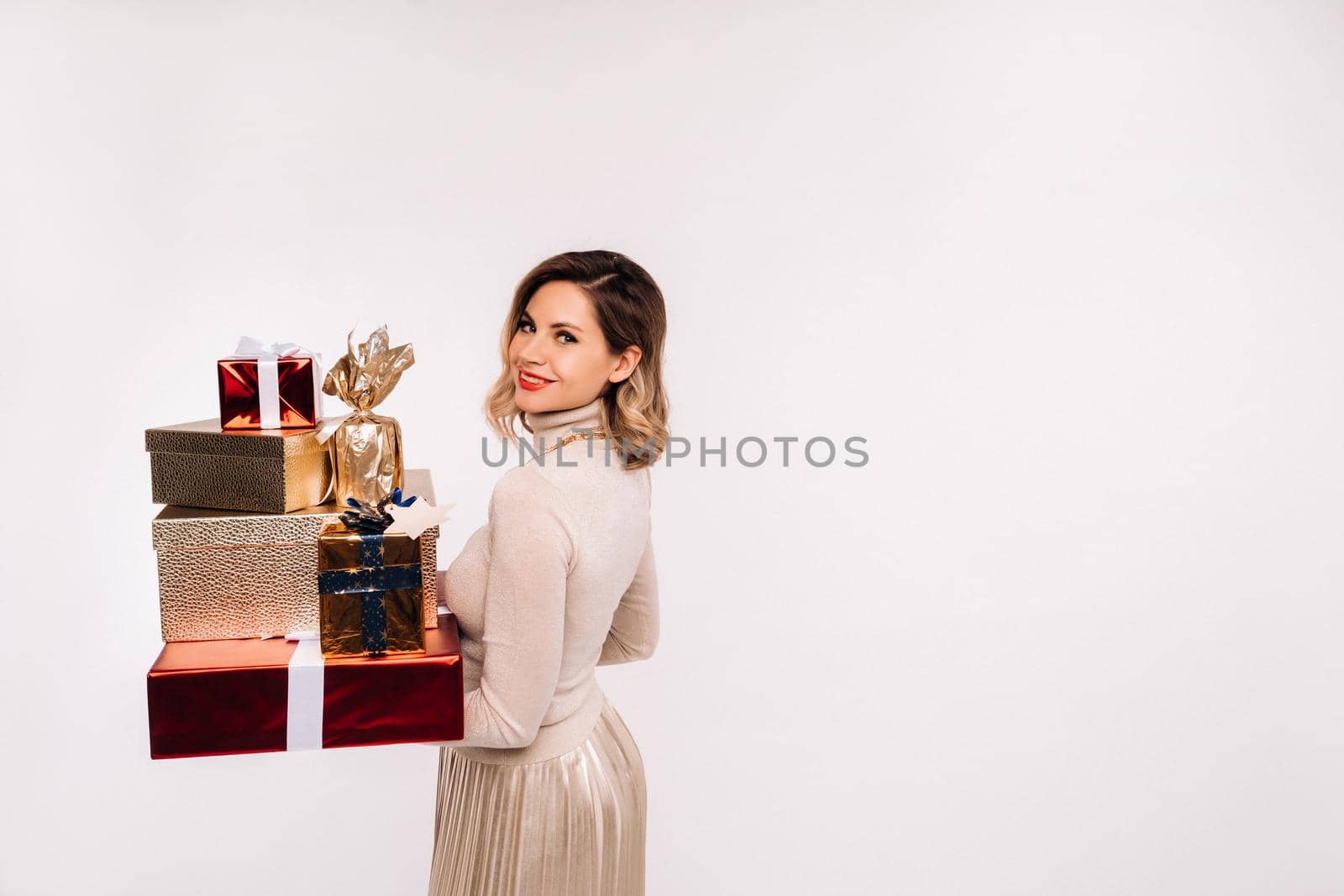 A girl in a skirt and jacket with a lot of gifts in her hands on a white background