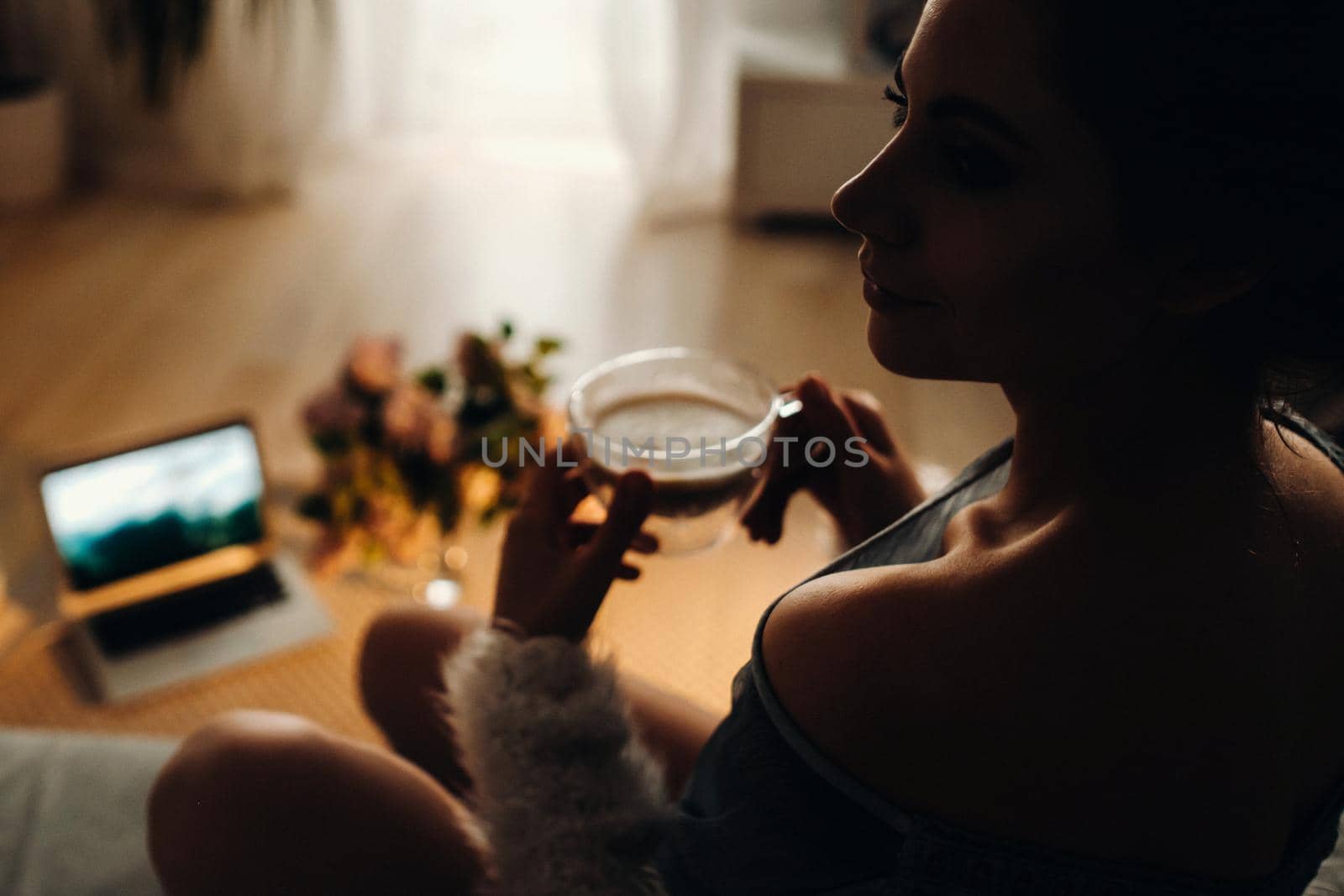 a relaxed girl at home drinks coffee and watches a movie.Domestic calm.The girl is sitting comfortably on the sofa and drinking coffee.